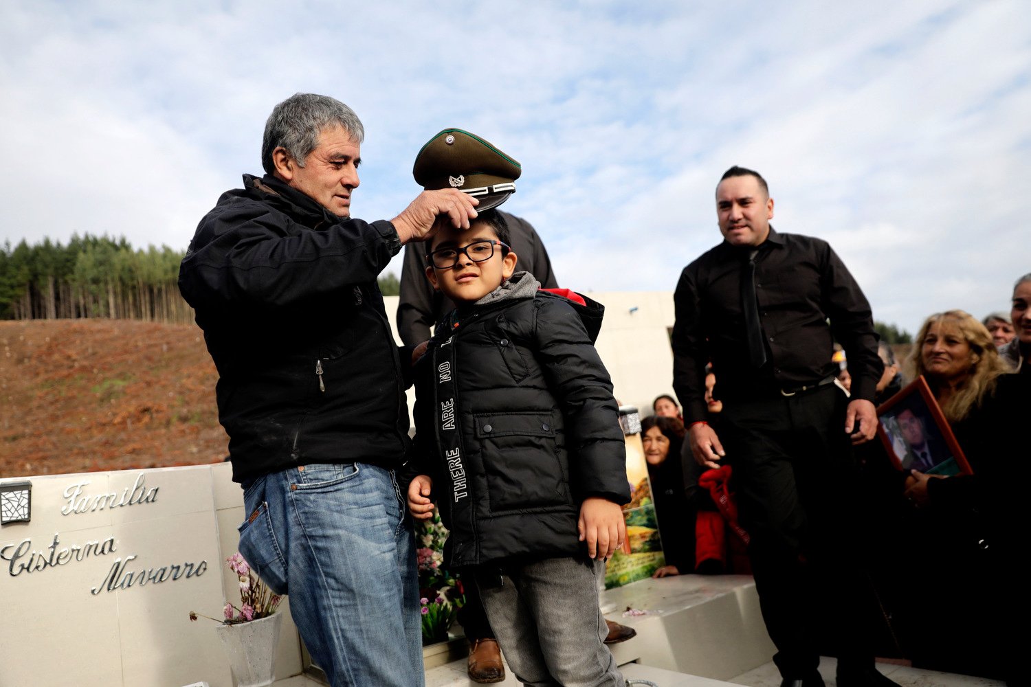  Carlos Cisterna places the police hat of his slain son, named after him, on his grandson Diego, as his son is buried in Lebu, Chile, Tuesday, April 30, 2024. Armed assailants ambushed and killed three law enforcement officers including Cisterna, in 