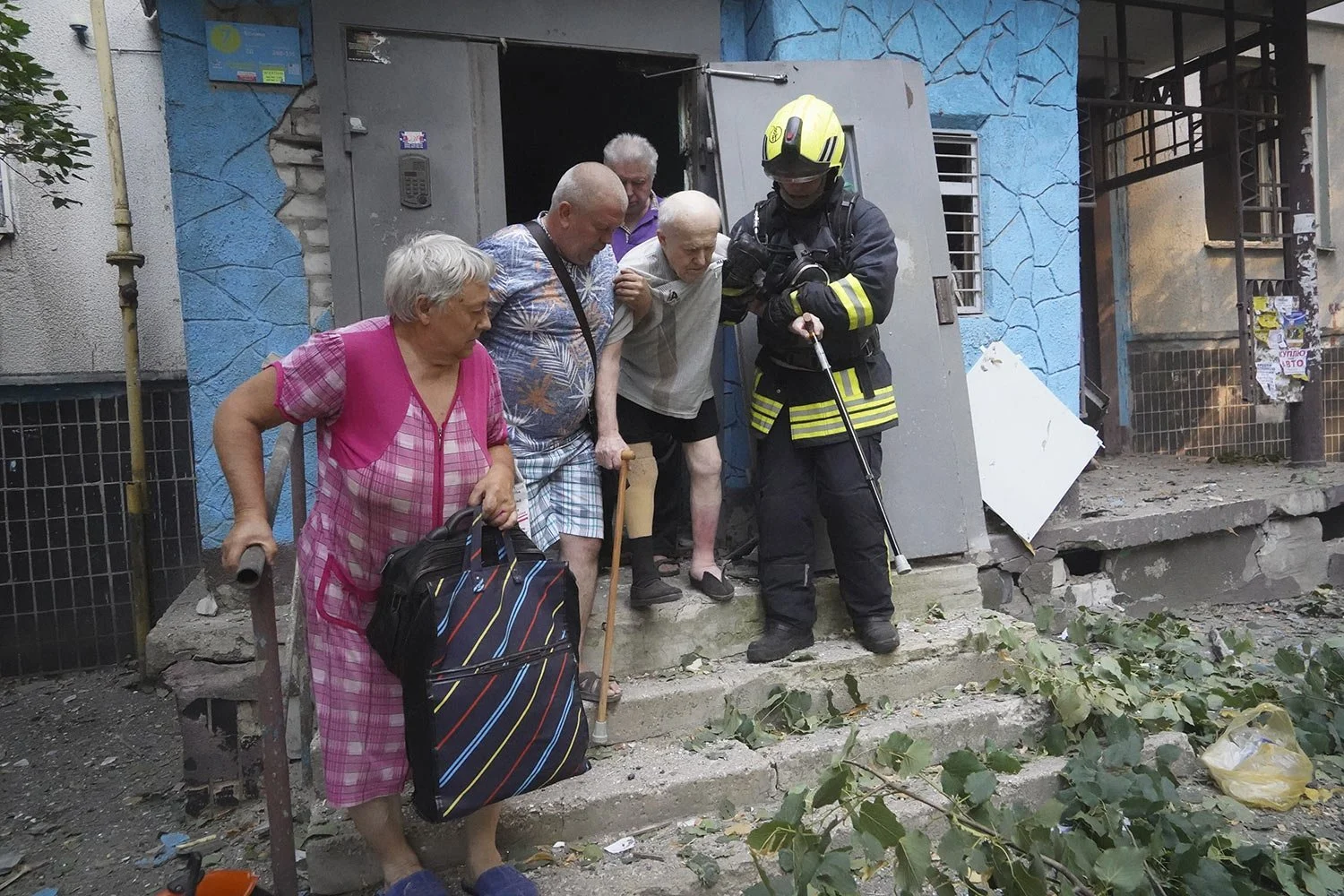  Rescuers help elderly residents to leave their damaged home after Russia's guided air bomb hit an apartment building in Kharkiv, Ukraine, Friday, Aug. 30, 2024. (AP Photo/Andrii Marienko) 