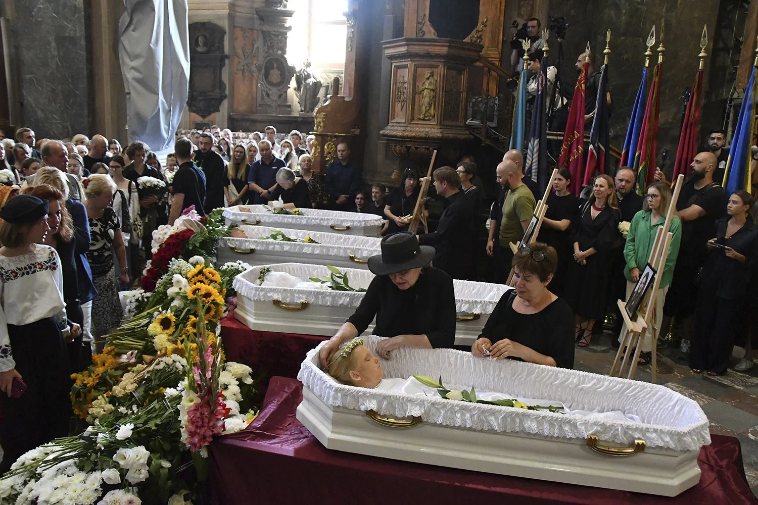  People mourn near the coffins of Yaroslav Bazylevych's family members during the funeral service in the Garrison Church in Lviv, Ukraine, Friday, Sept. 6, 2024. (AP Photo/Mykola Tys) 