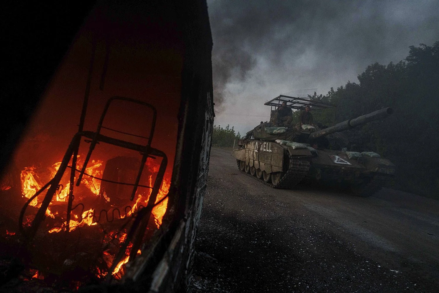 A Ukrainian tank passes by a burning car near the Russian-Ukrainian border, Sumy region, Ukraine, Wednesday, Aug. 14, 2024. (AP Photo/Evgeniy Maloletka) 