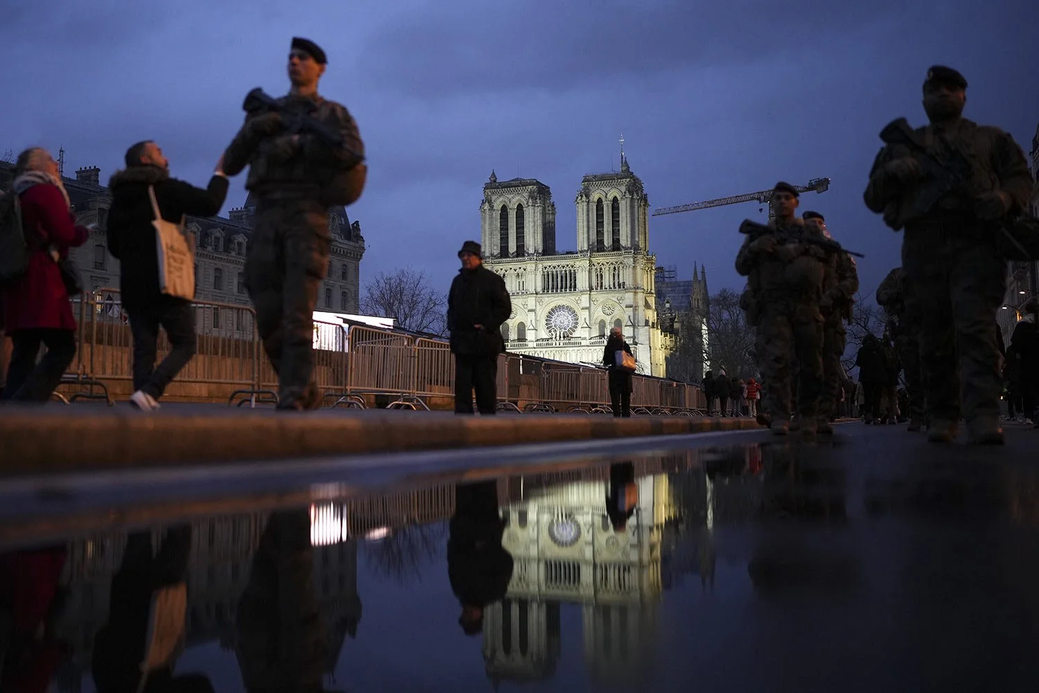  People walk past as France's iconic Notre Dame Cathedral is reflected in a puddle Saturday, Dec. 7, 2024 in Paris before the formal reopening for the first time since a devastating fire nearly destroyed the 861-year-old landmark in 2019. (AP Photo/A