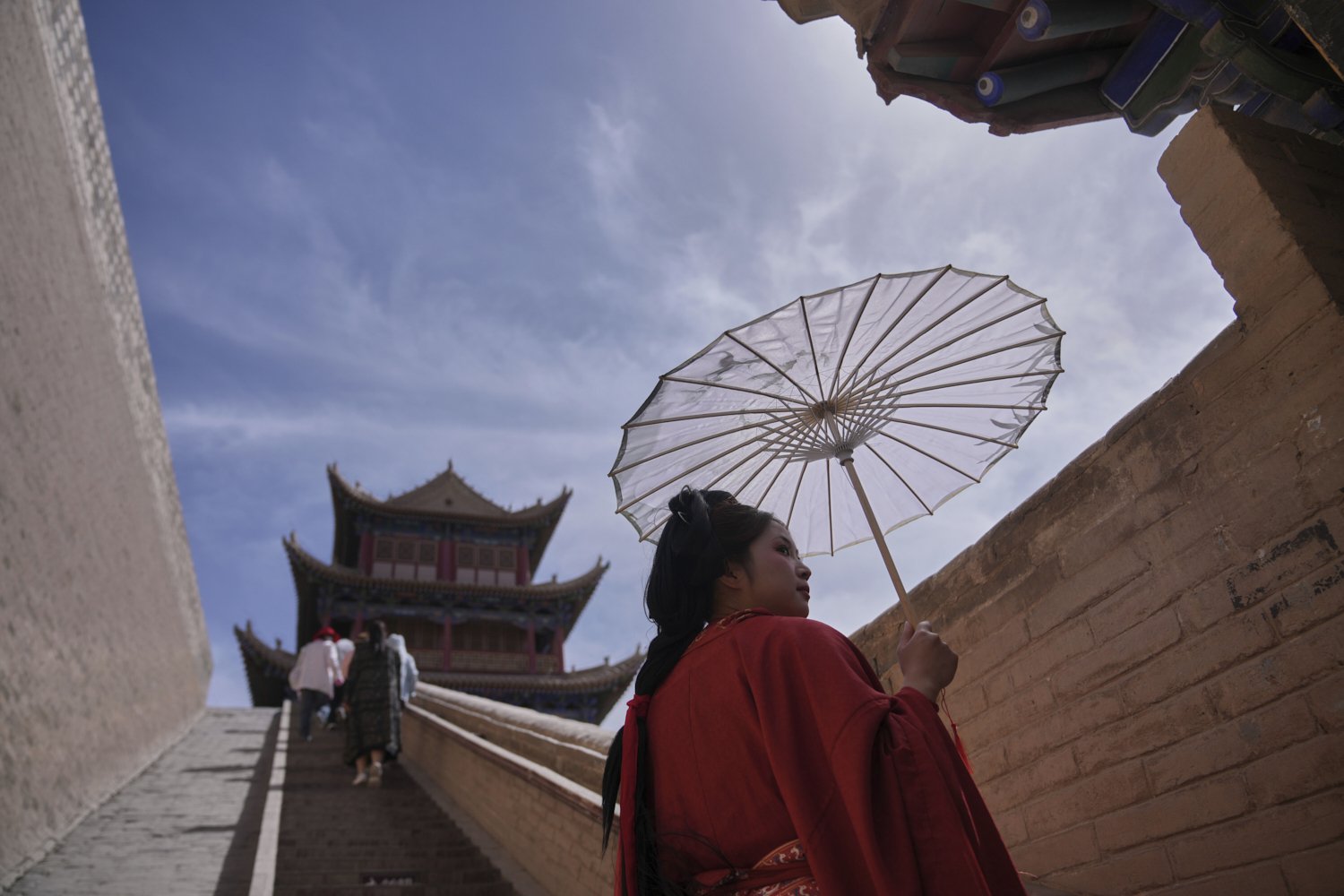A woman is dressed in traditional costume as she and visitors tour Jiayu Pass, a strategic point of the Great Wall of China along the ancient "Silk Road," near the city of Jiayuguan in China's northwestern Gansu province, Tuesday, April 22, 2025. (A