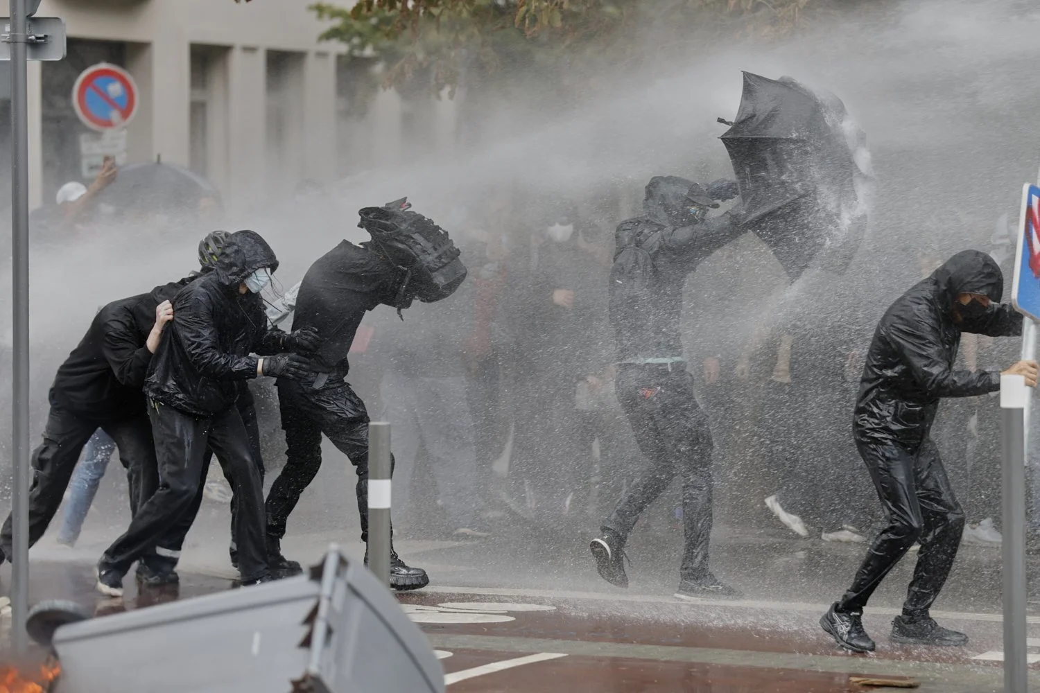 Protesters of the "Block Everything" movement take cover from a spraying water canon in Lille, northern France, Wednesday, Sept. 10, 2025. (AP Photo/Jean-Francois Badias)