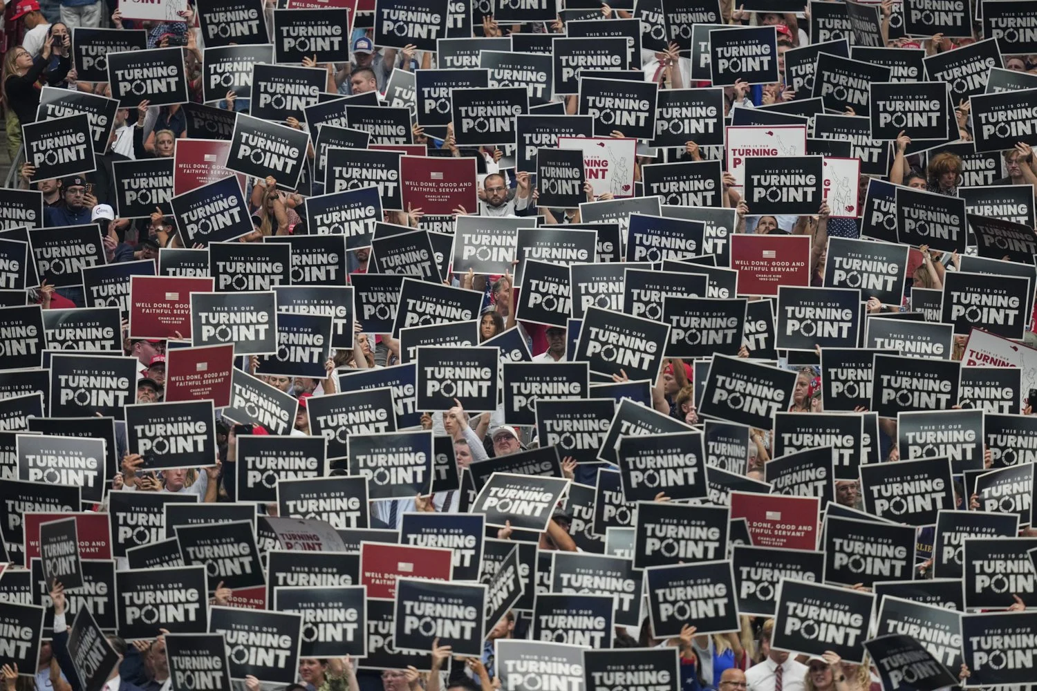 People hold up signs during a memorial for conservative activist Charlie Kirk, Sunday, Sept. 21, 2025, at State Farm Stadium in Glendale, Ariz. (AP Photo/John Locher)