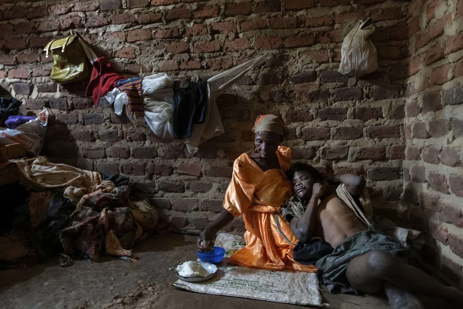 Alice Mary Nasanga, who is about 70 and was banished by members of her family after she was accused of witchery, holds her disabled son, Ibrahim Kamya, 30, as she feeds him on the floor of the home they share in Nabalanga, Uganda, Saturday, Nov. 16,