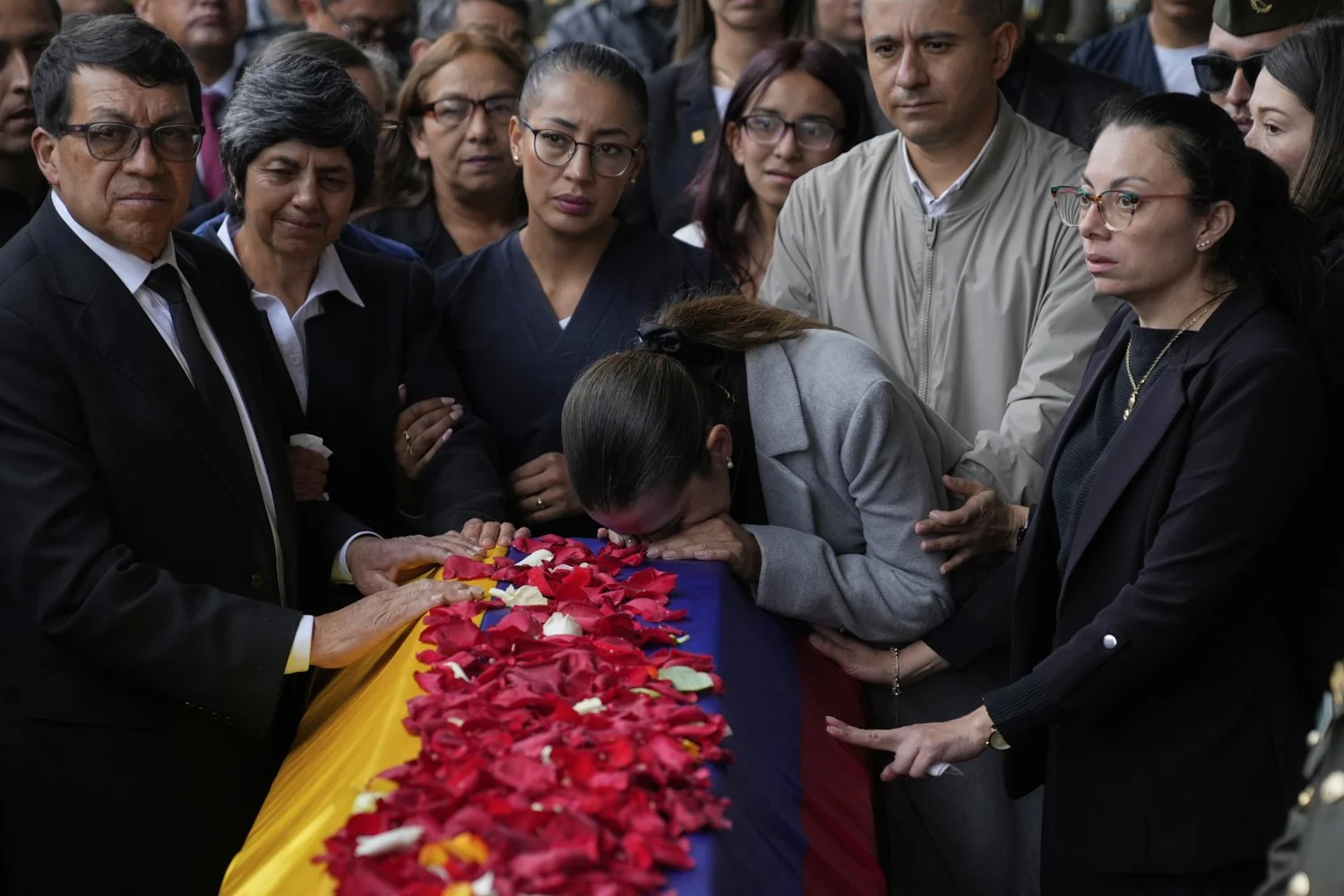 Police Maj. Adriana Pinzon kisses the coffin of her husband, Capt. Francisco Merchan, a police pilot killed when his helicopter was shot down by a dissident faction of the former FARC guerrilla group, as his father, Bernardo Merchan, and other relat