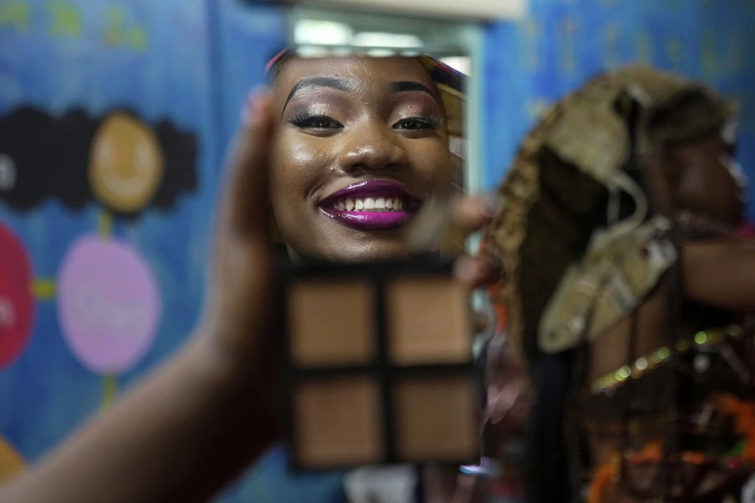 A model is reflected in a mirror applying makeup during the Mr. and Mrs. Kibera leadership contest held on International Youth Day in Nairobi, Kenya, Aug. 12, 2025. (AP Photo/Brian Inganga)
