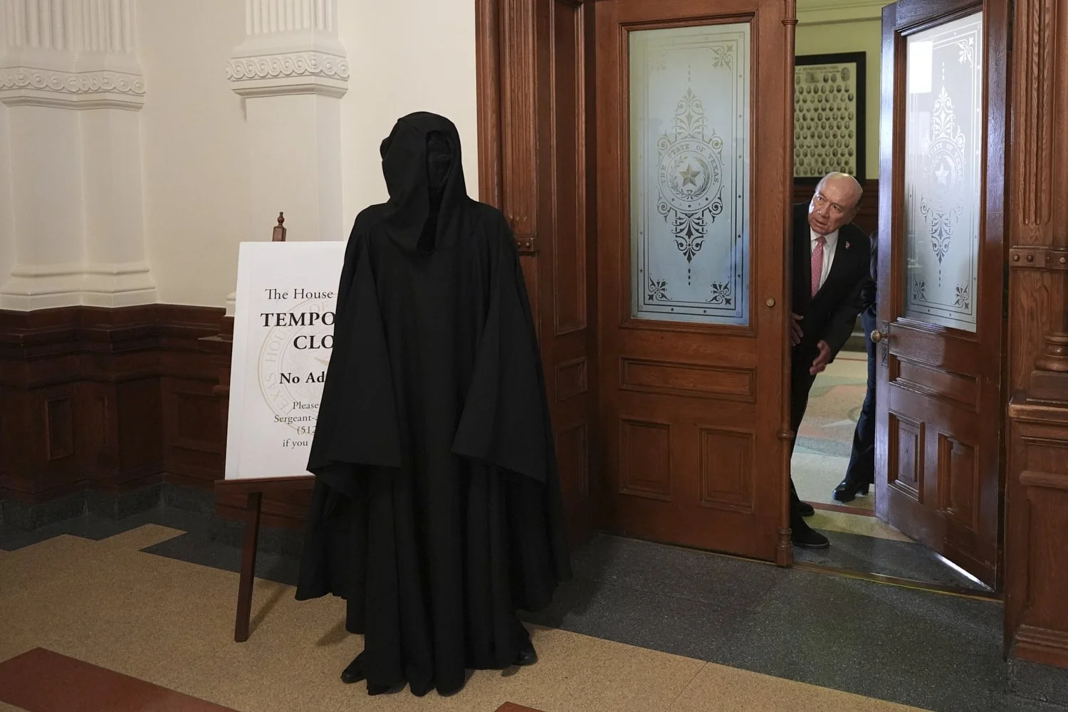 Texas state Sen. Juan "Chuy" Hinojosa, right, looks at a protester dressed as death outside of the House Chamber where Democratic Texas state Rep. Nicole Collier refuses agree to an around-the-clock police escort in Austin, Texas, Aug. 19, 2025. (AP