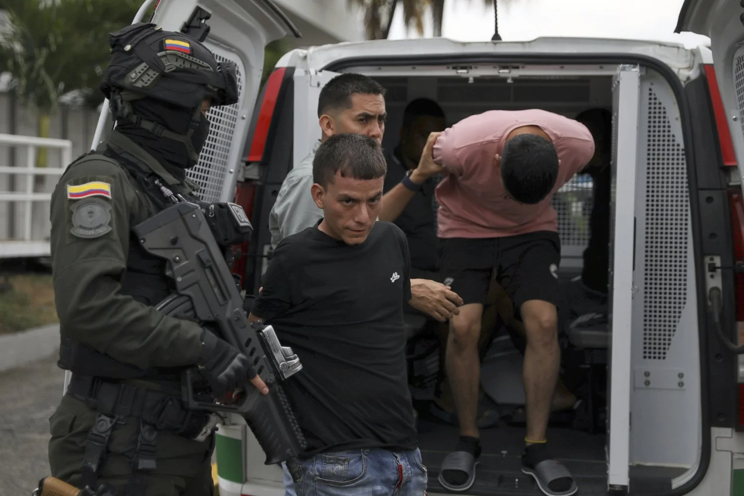 Police escort two arrested suspects in the detonation of a car bomb at an Air Force base to police headquarters in Cali, Colombia, Aug. 25, 2025. (AP Photo/Santiago Saldarriaga)