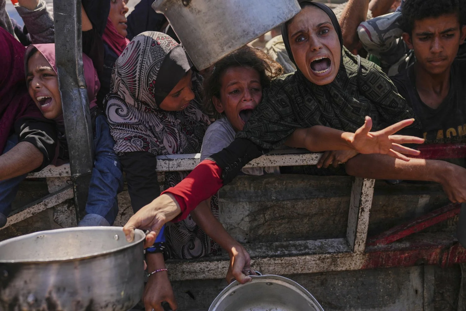 Palestinians struggle to get donated food at a community kitchen in Gaza City, northern Gaza Strip, Aug. 4, 2025. (AP Photo/Jehad Alshrafi)