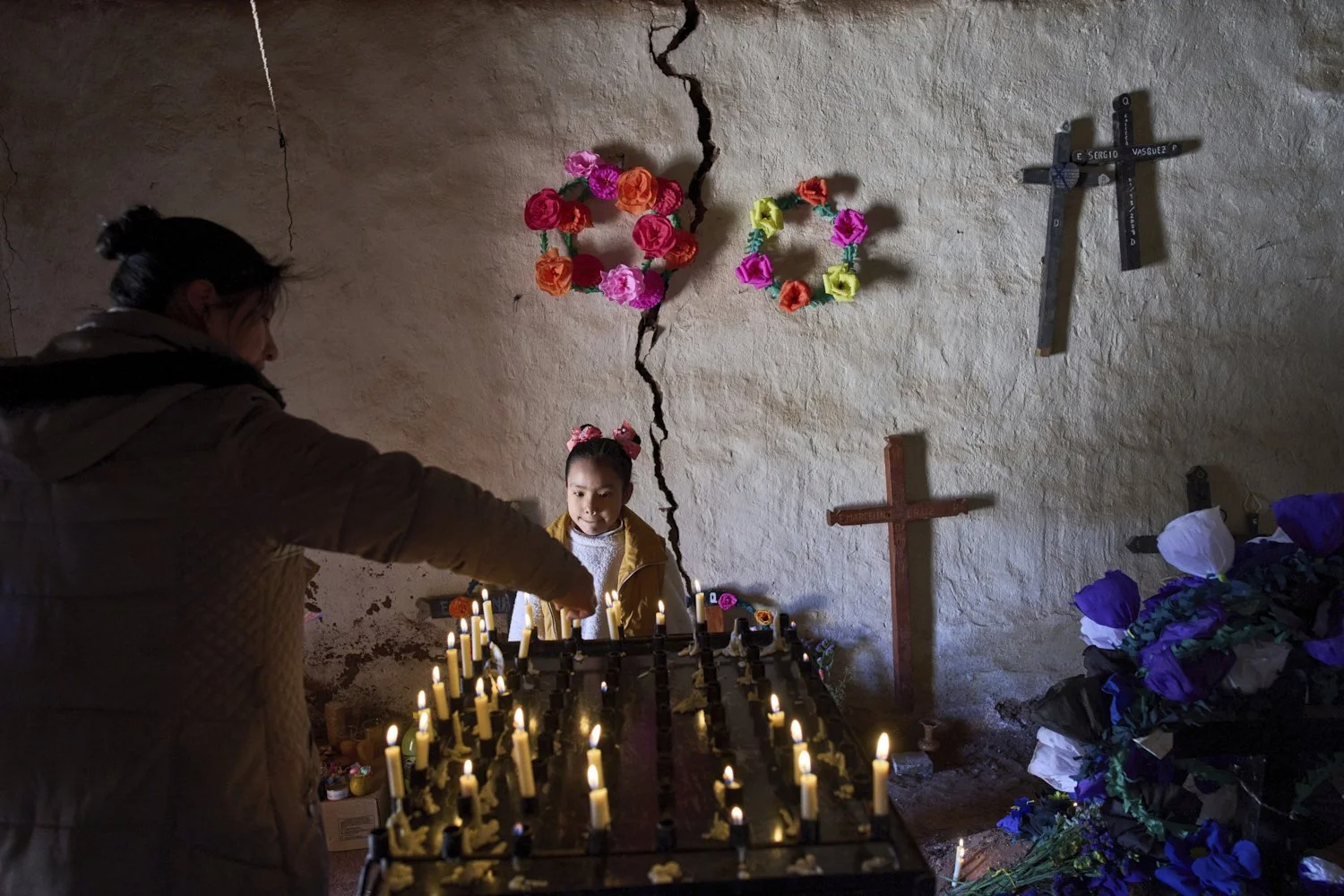  Nina Valentina Nieva helps her uncle Lorena Plaza light a candle in memory of her mother, Lorena Luca, inside a chapel at the cemetery during Day of the Dead celebrations in Susques, Jujuy province, Argentina, Saturday, Nov. 1, 2025. (AP Photo/Rodri