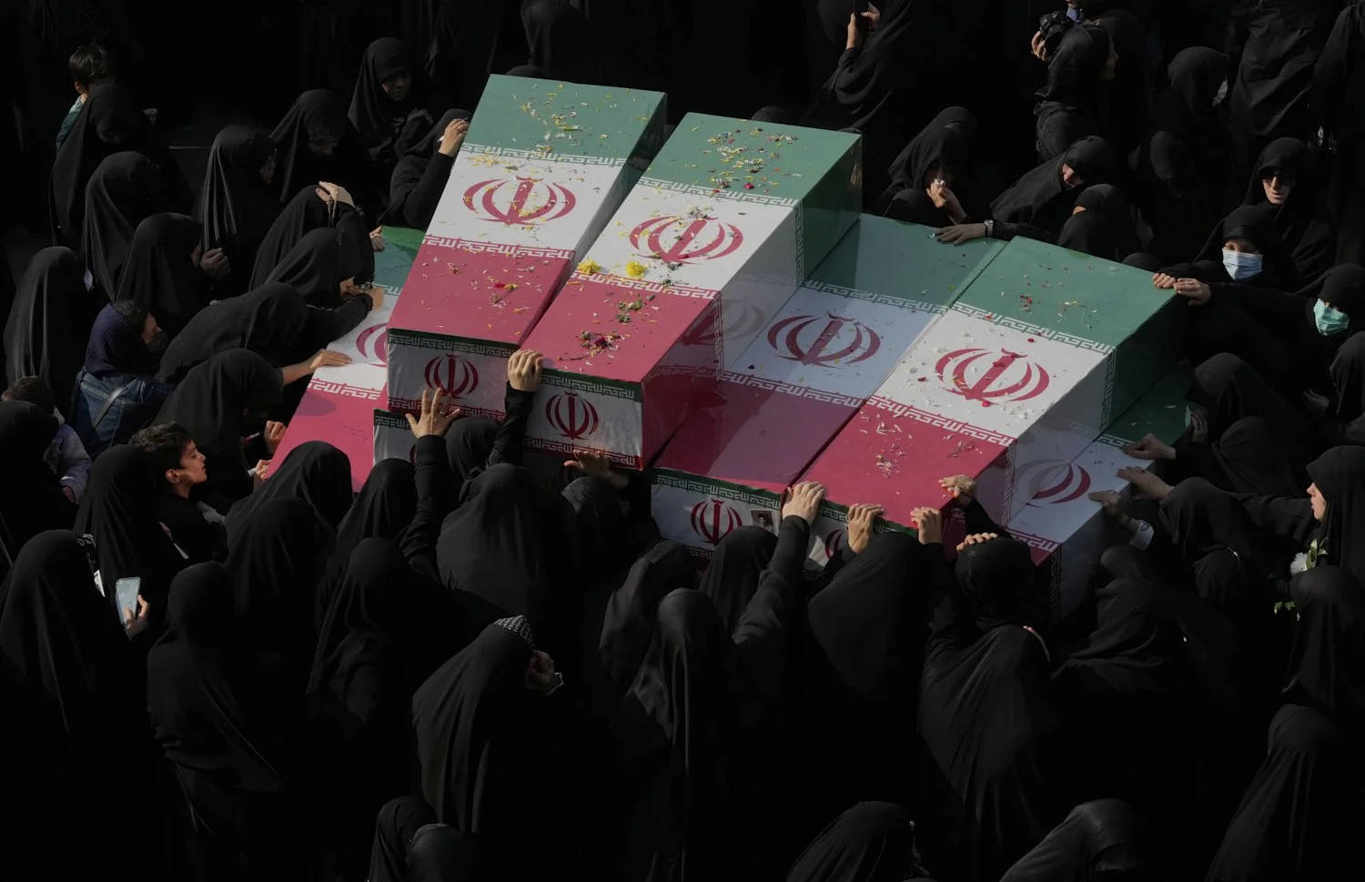 Mourners gather around the flag-draped coffins of unknown Iranian soldiers who were killed in the 1980-1988 Iraq-Iran war whose remains were recently recovered from the battlefields, during the funeral ceremony in Tehran, Iran, Monday, Nov. 24, 2025