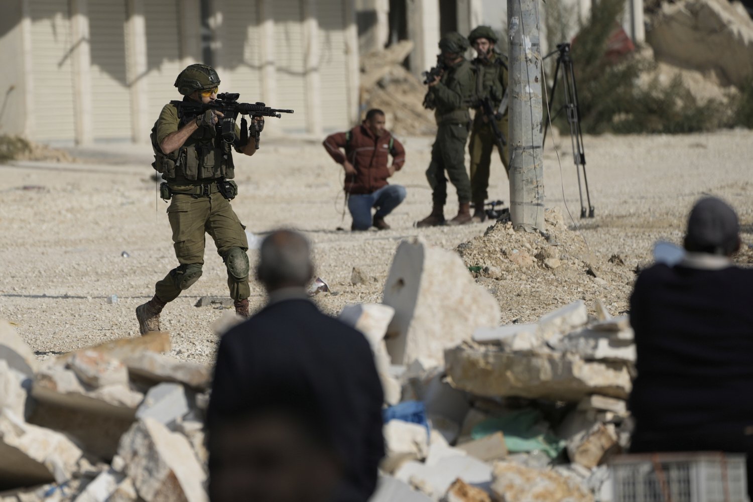  An Israeli soldier aims his weapon to disperse people taking part in a protest calling for the return of displaced Palestinians to their houses in the Nur Shams refugee camp in the West Bank city of Tulkarem on Tuesday, Nov. 18, 2025. (AP Photo/Majd