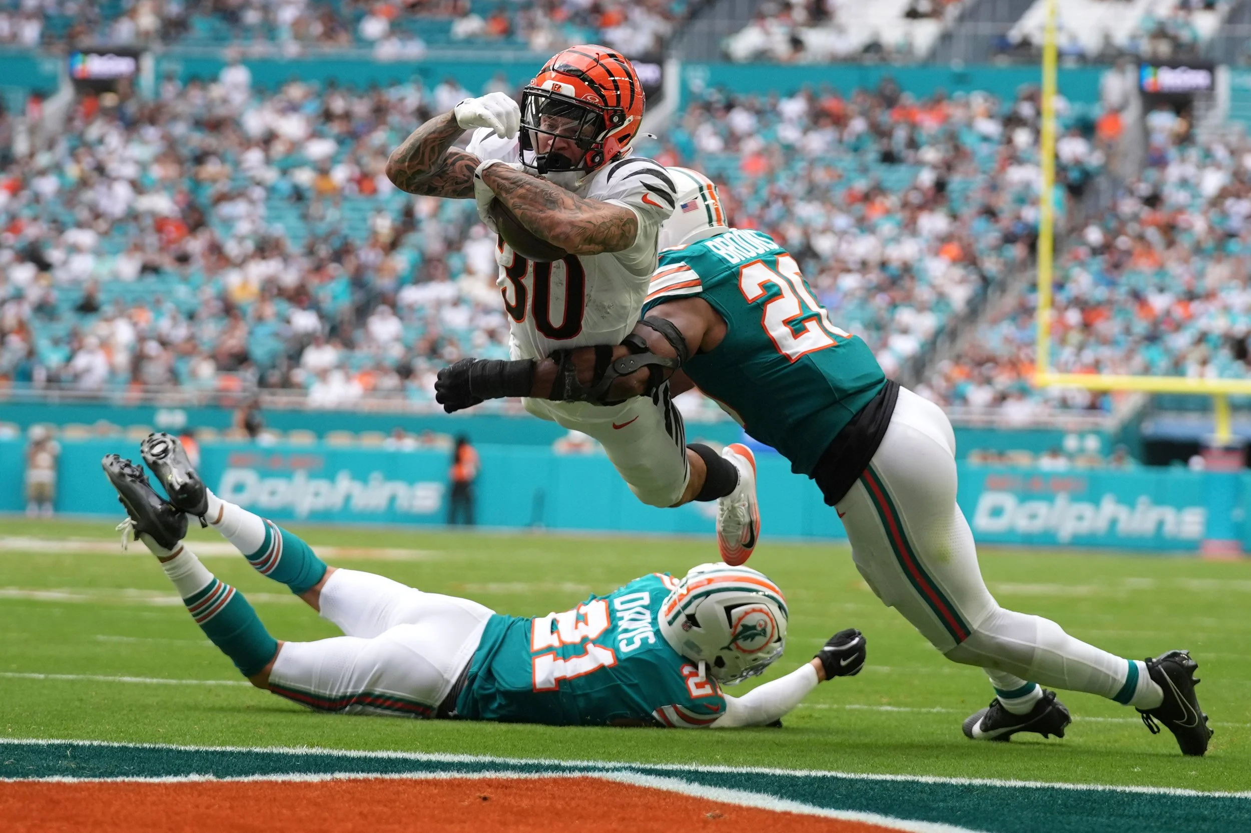  Cincinnati Bengals running back Chase Brown, center, breaks a tackle by Miami Dolphins linebacker Jordyn Brooks, right, for a touchdown during the second half of an NFL football game, Dec. 21, 2025, in Miami Gardens, Florida. (AP Photo/Lynne Sladky)