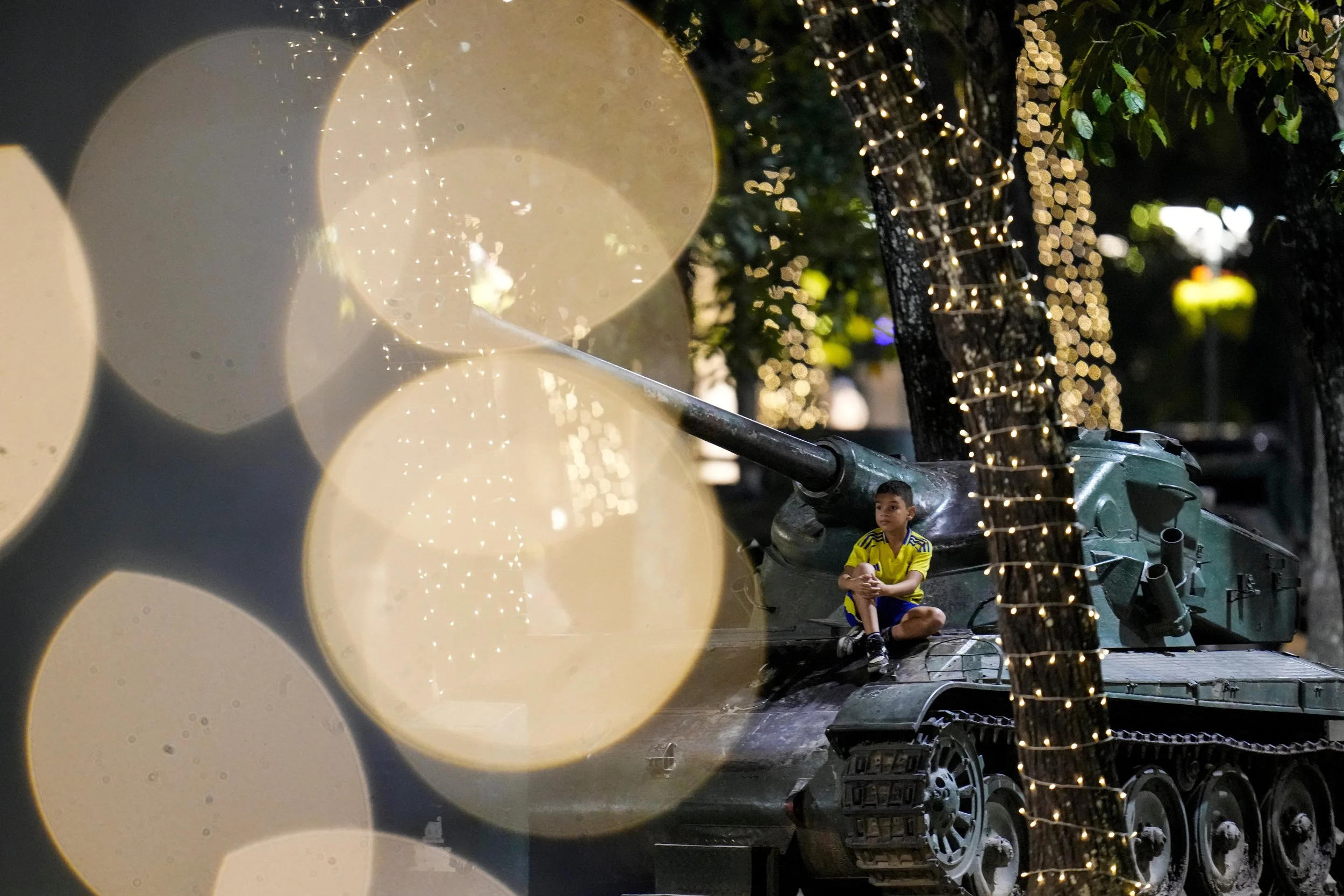  A child sits on an armored vehicle on display among Christmas lights in Caracas, Venezuela, Dec. 23, 2025. (AP Photo/Matias Delacroix) 