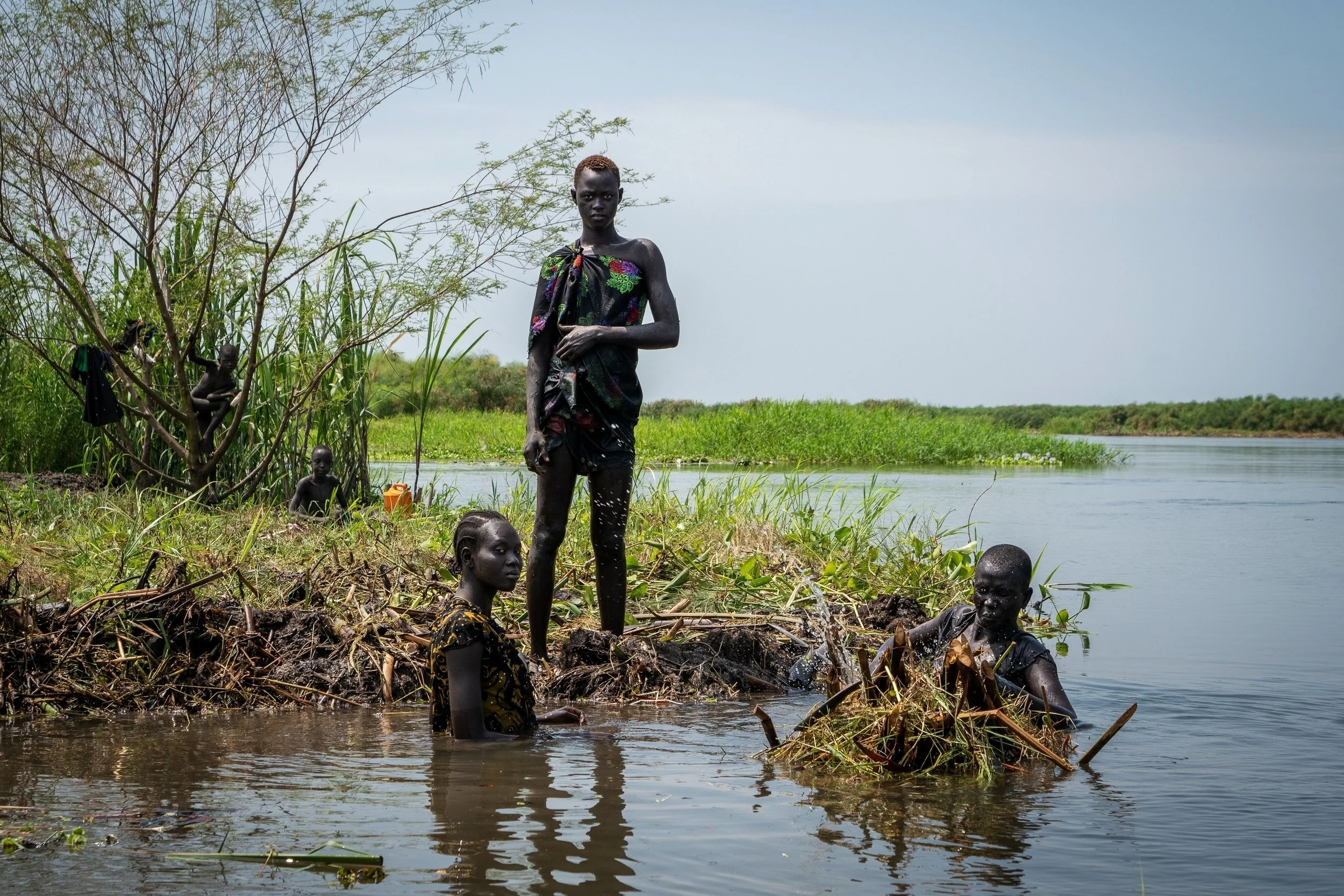  Ayen Deng Duot, far right, and her family reinforce their island with vegetation and mud from the swamp to prevent their home from being flooded along the Nile River in Akuak, South Sudan, Nov. 8, 2025. (AP Photo/Florence Miettaux) 