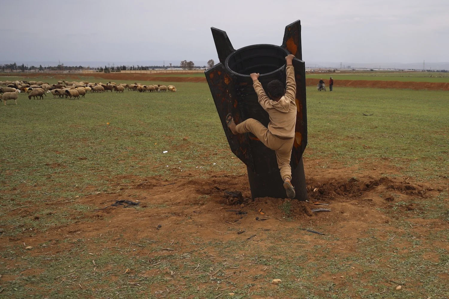  A boy tries to climb on an unexploded Iranian projectile that landed in an open field on the outskirts of Qamishli, eastern Syria, March 4, 2026.(AP Photo/Baderkhan Ahmad) 