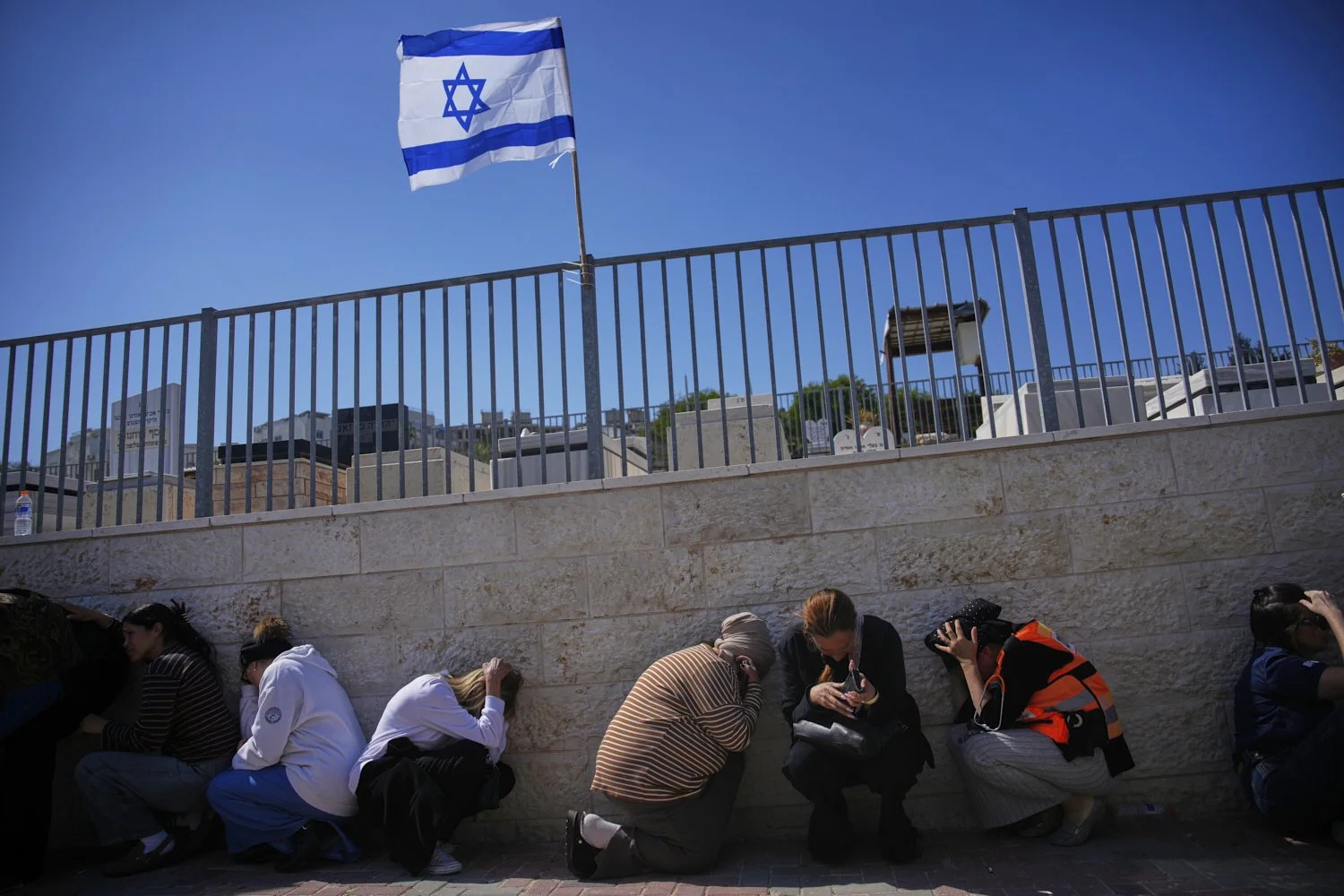  Mourners take cover while air-raid sirens warn of incoming missiles launched by Iran toward Israel during the funeral of Sarah Elimelech and her daughter Ronit, who were killed in an Iranian missile attack, in Beit Shemesh, Israel, March 2, 2026. (A
