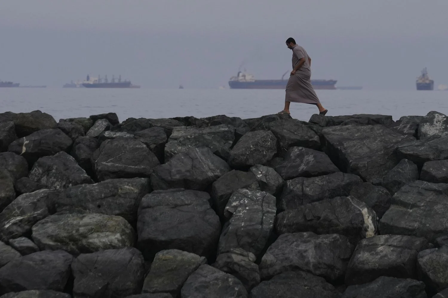  A man walks along the shore as oil tankers and cargo ships line up in the Strait of Hormuz, seen from Khor Fakkan, United Arab Emirates, March 11, 2026. (AP Photo/Altaf Qadri) 