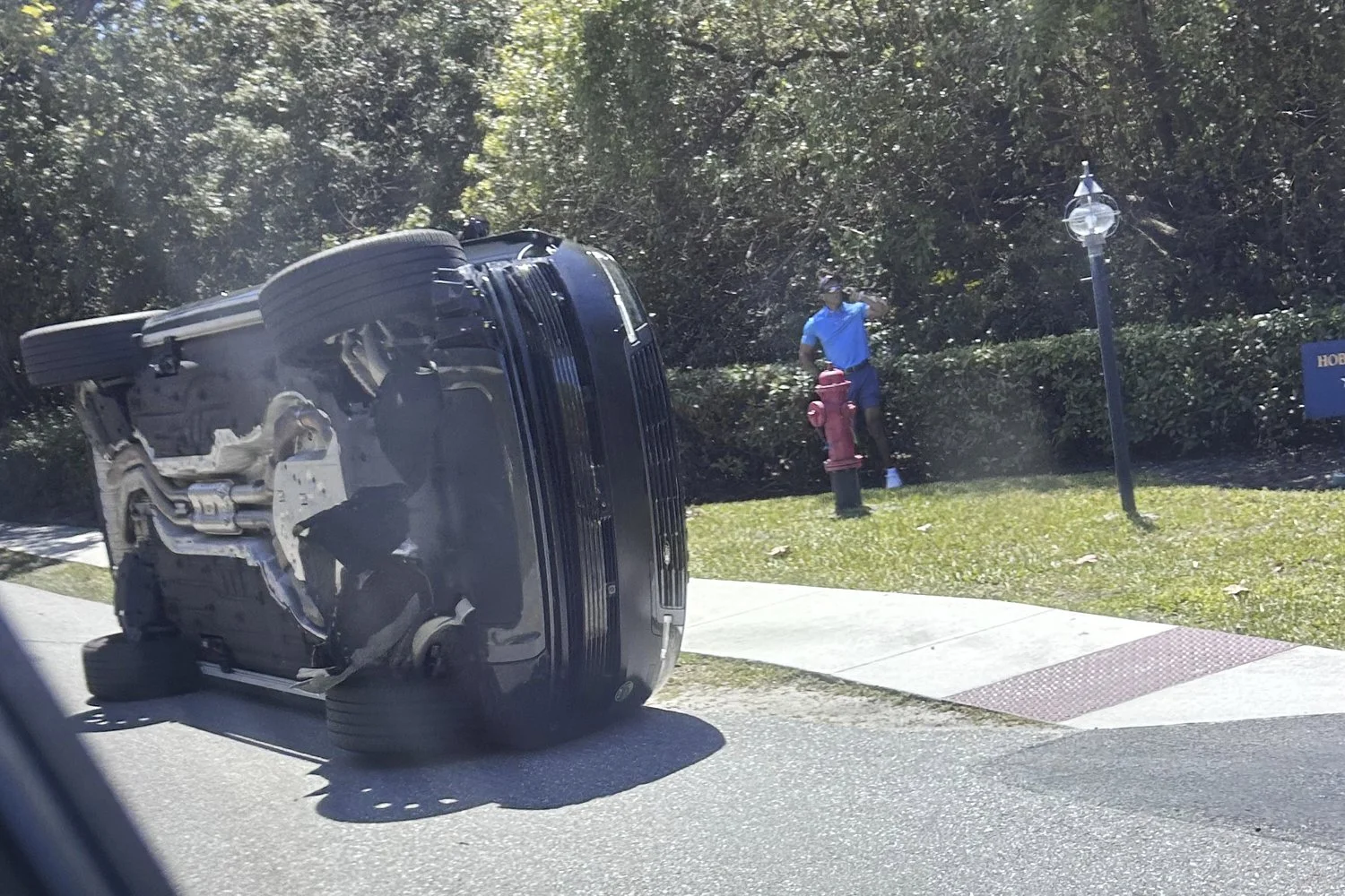  Golfer Tiger Woods stands by his overturned vehicle in Jupiter Island, Fla., March 27, 2026. (AP Photo/Jason Oteri) 
