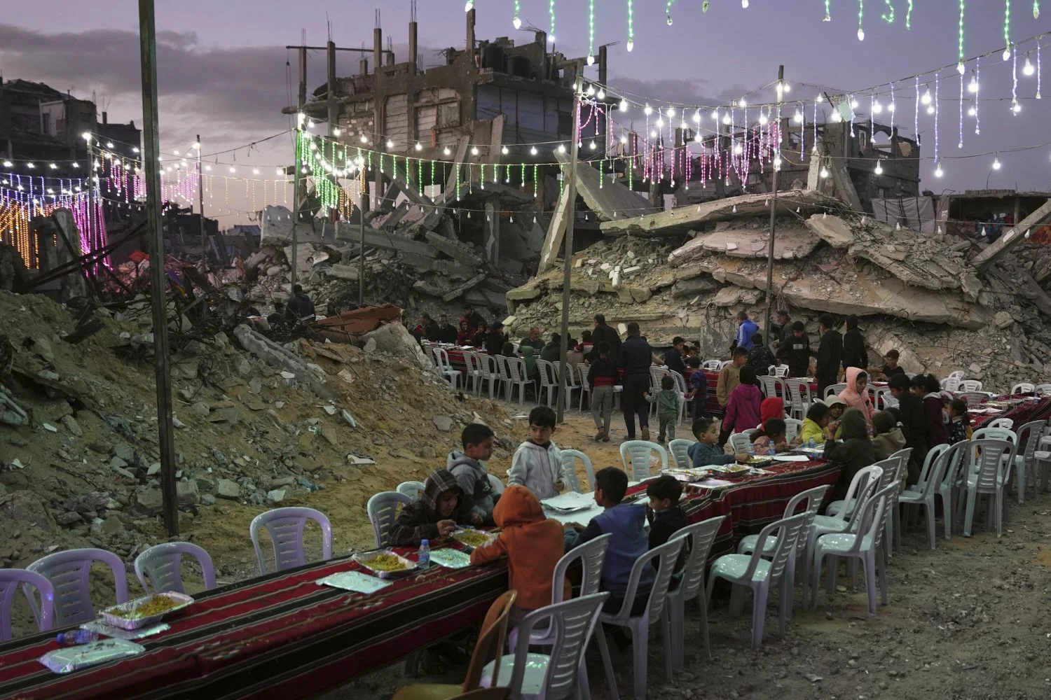  Palestinians gather amid the rubble of destroyed buildings as they gather for their fast-breaking meal during the Muslim holy month of Ramadan, in Khan Younis, Gaza Strip, Feb. 19, 2026. (AP Photo/Abdel Kareem Hana) 