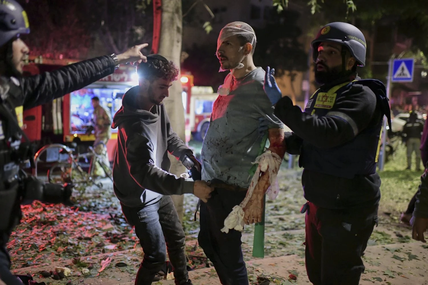  Rescue workers bandage a wounded man and provide first aid at the site of a direct hit from an Iranian missile strike in Tel Aviv, Israel, Feb. 28, 2026. (AP Photo/Tomer Neuberg) 