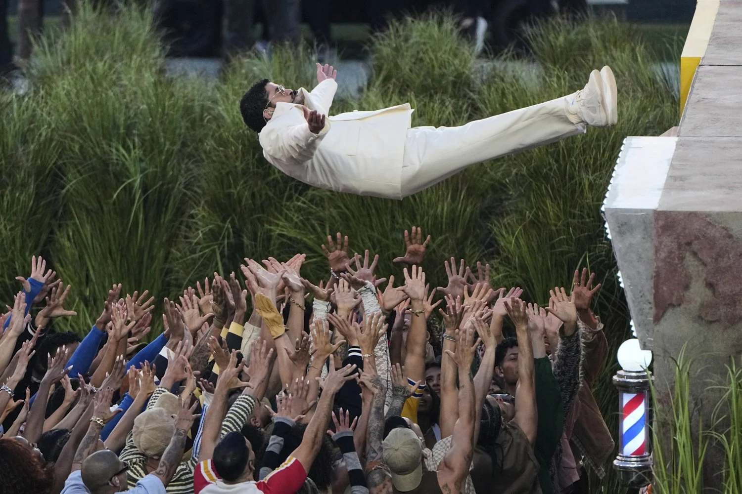  A crew reaches up to catch Bad Bunny during his NFL Super Bowl LX halftime performance, in Santa Clara, Calif., Feb. 8. 2026. (AP Photo/Charlie Riedel) 