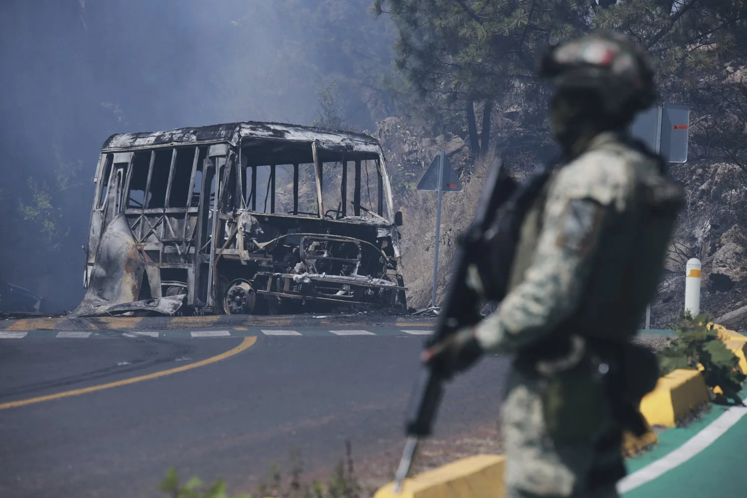  A soldier stands guard by a charred vehicle after it was set on fire, in Cointzio, Mexico, Feb. 22, 2026, following the death of the leader of the Jalisco New Generation Cartel, Nemesio Oseguera, known as "El Mencho." (AP Photo/Armando Solis) 