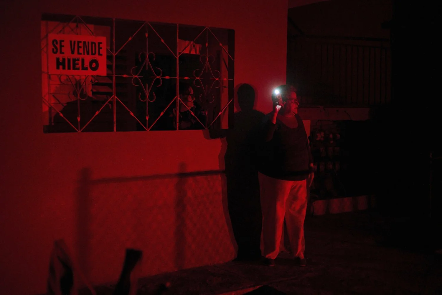 A woman holds up a cell phone flashlight as she chats with a friend during a scheduled power outage as part of energy rationing in Santa Cruz del Norte, home to one of Cuba's largest thermoelectric plants, Feb. 3, 2026. (AP Photo/Ramon Espinosa) 