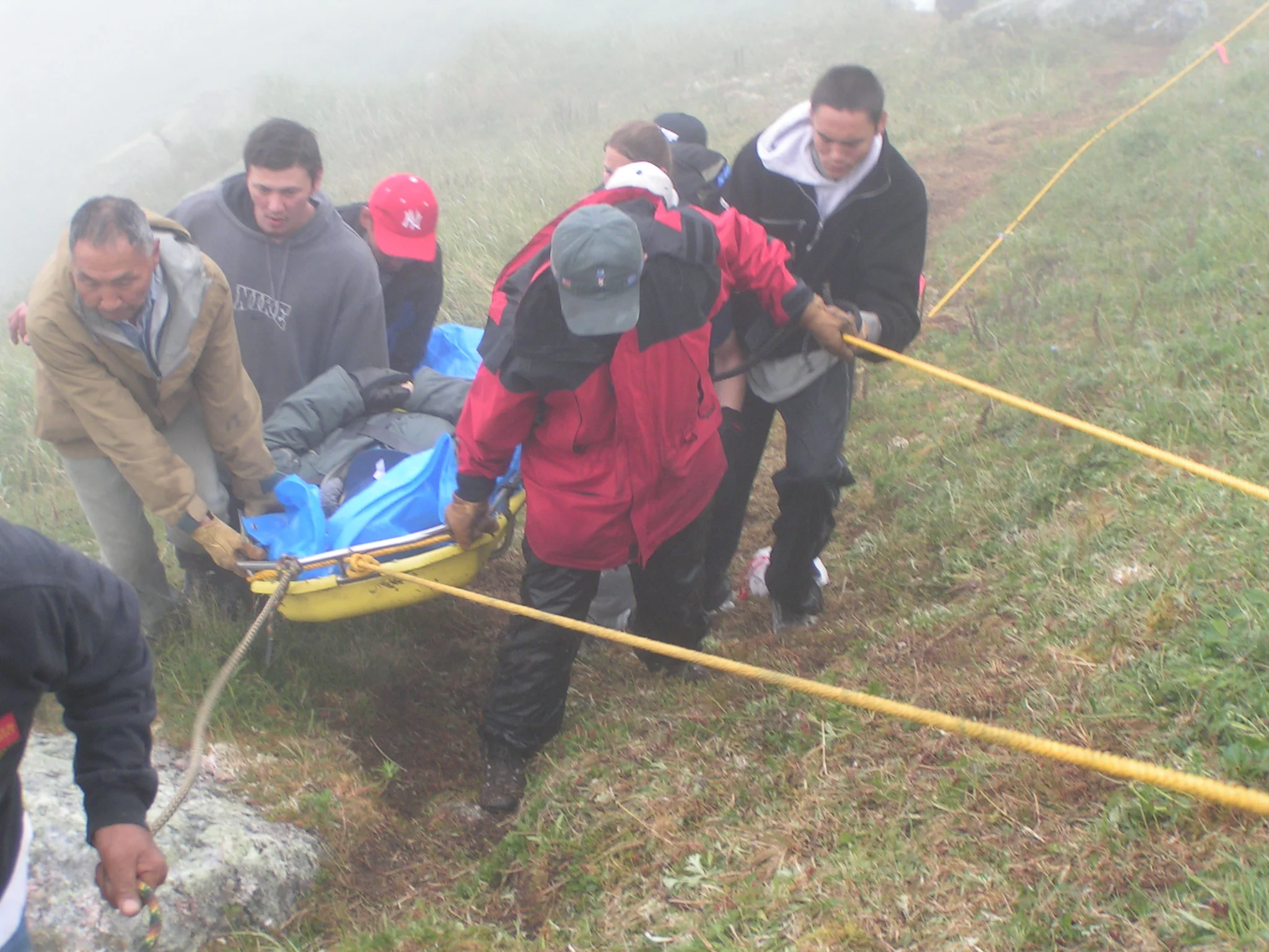 Chico helps a team as it carries the oldest Elder of the King Islanders the top of the island so he could be helicopter-evacuated after his health deteriorated. A storm delayed the rescue for two days. King Island, 2004.