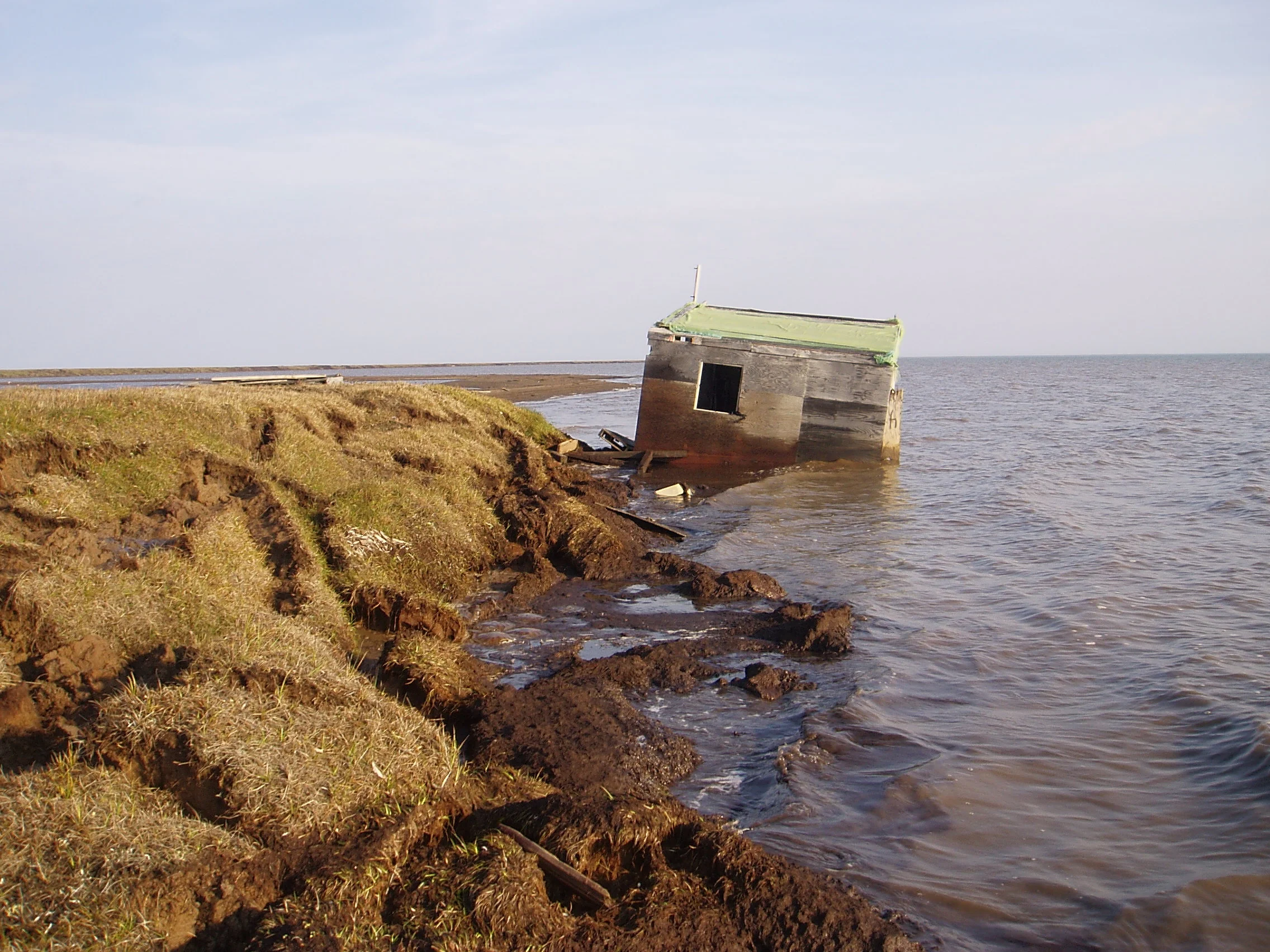 A cabin along the Arctic Alaska coastline was recently washed into the ocean because the bluff it was sitting on top of was eroded away. Photo: Benjamin Jones, USGS