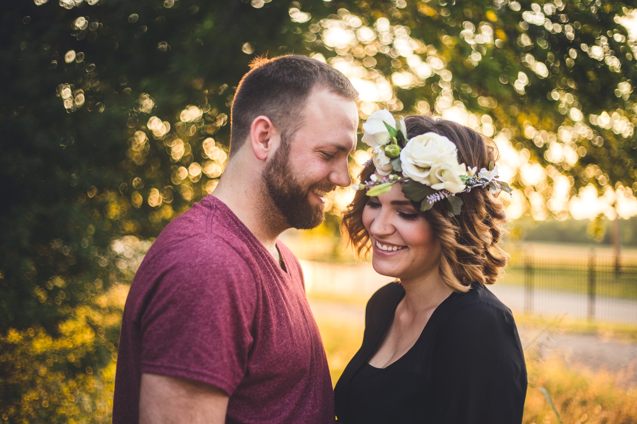 A photograph of a young couple standing facing each other and smiling in this outdoor, natural light couples photography by L+R Photography