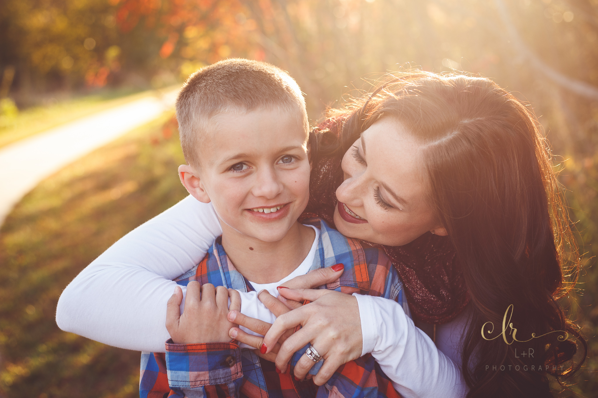 A photograph of a mother embracing her young son in the golden sunset, in an autumn family photography by L&R Photography