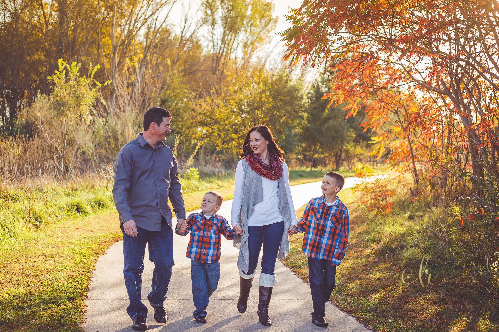 A photograph of a family of four, walking down a park path and holding hands - Tulsa, Oklahoma Family Photographer