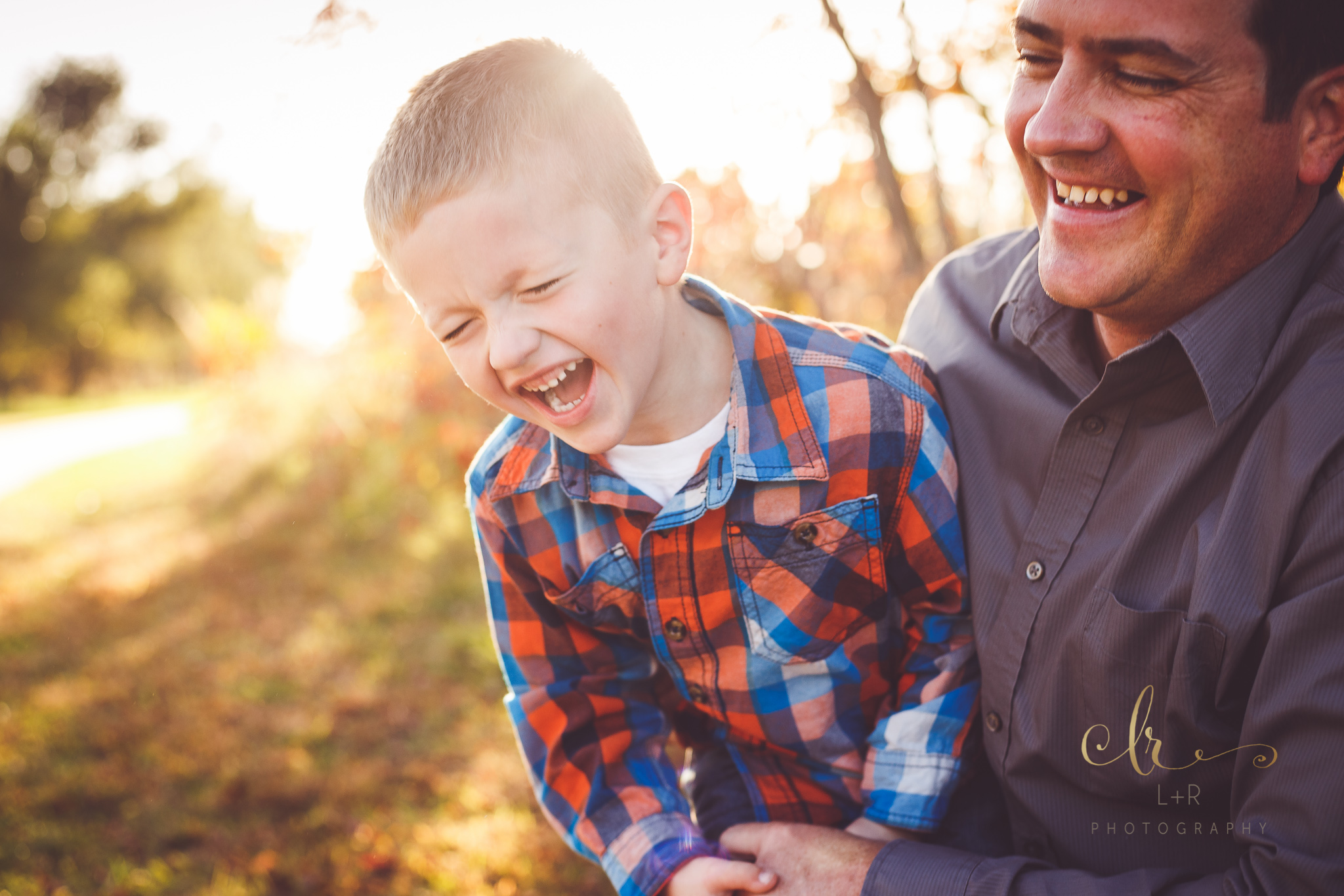 A photograph of a young boy laughing while being held by his father