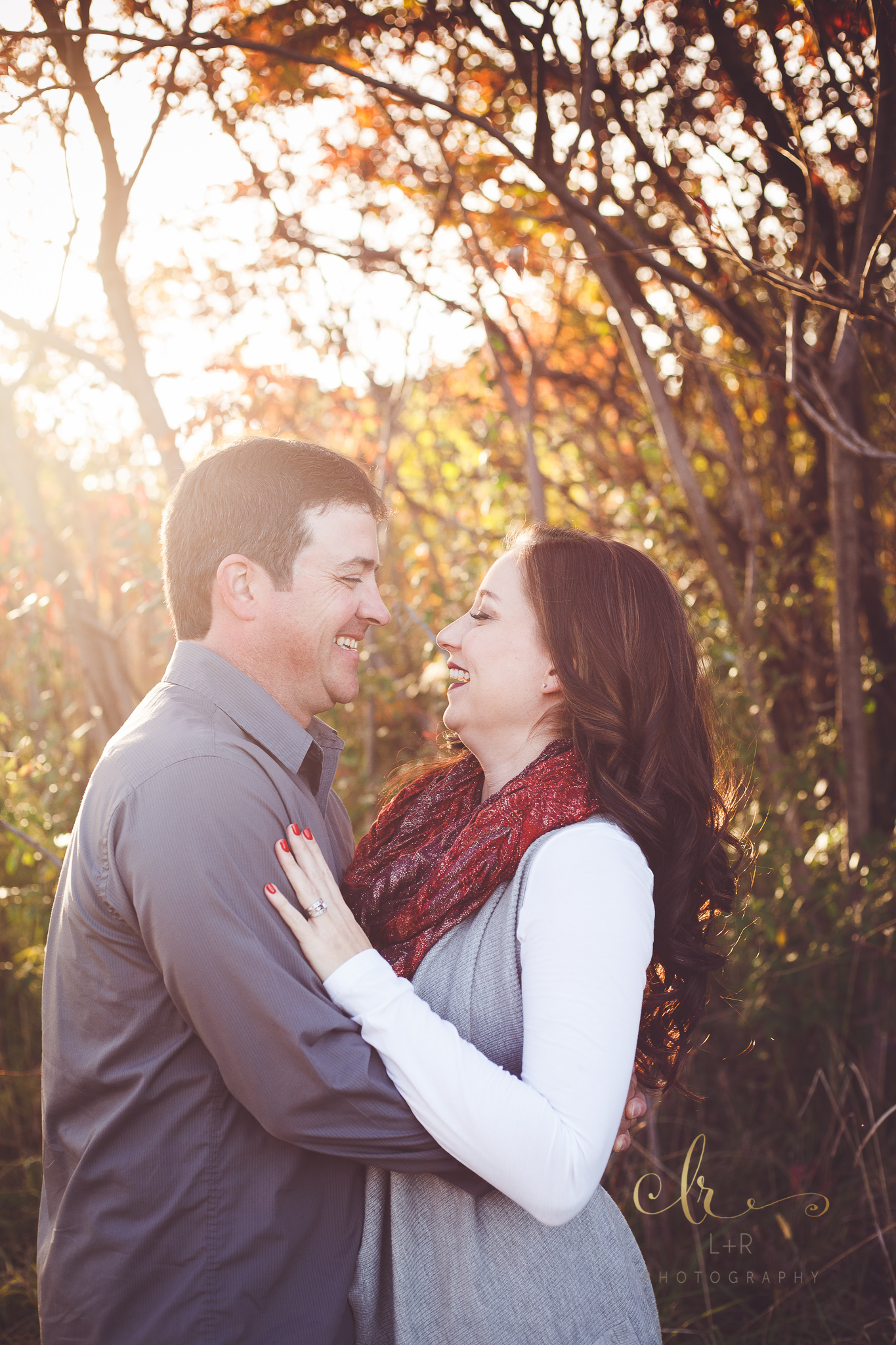 A young mother and father gaze into each other's eyes with the golden hour sunset behind them in this family photography session by L&R Photography