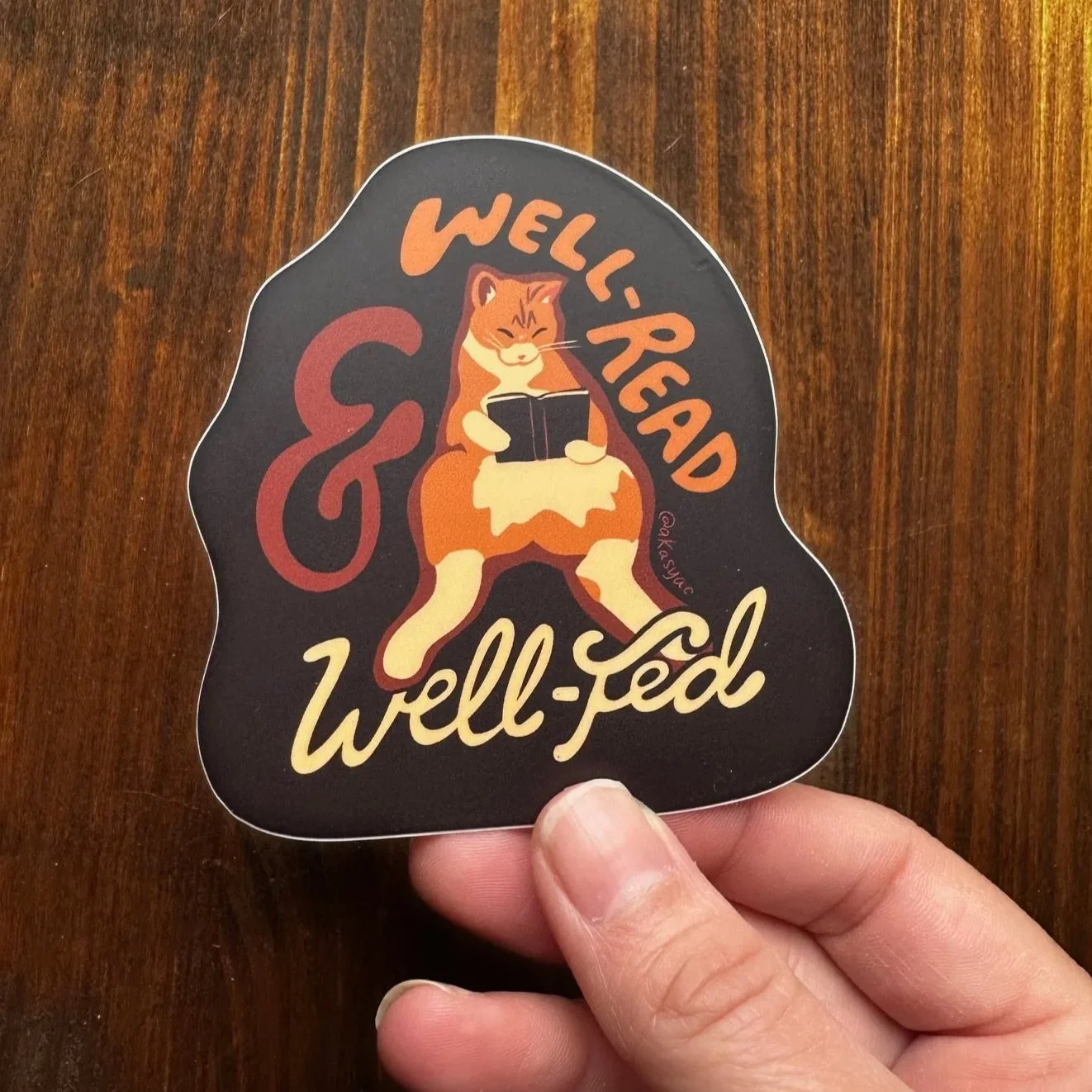 Well+Read+and+Well+Fed+tabby+cat+sticker+in+hand+wood+bg.jpg