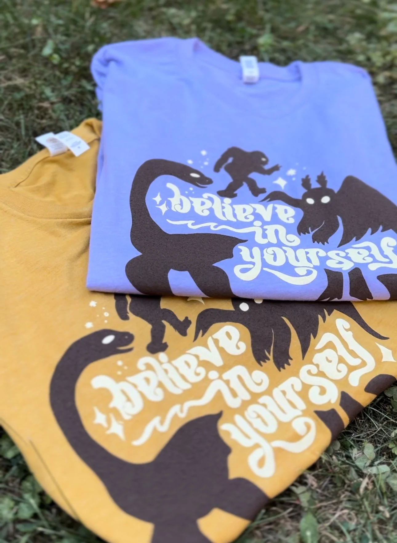 Believe in Yourself cryptid Tees product photos on grass both colors.jpg