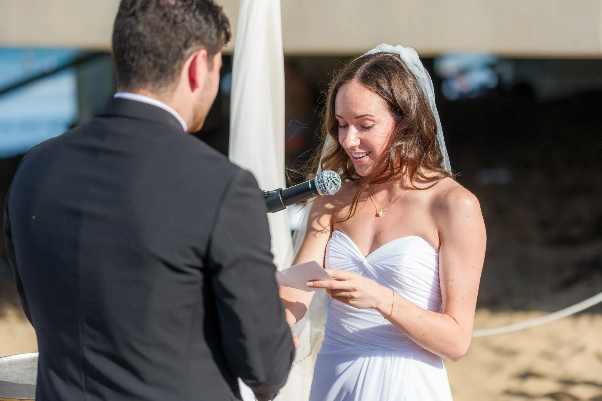 Bride reading vows into a microphone during an oceanfront wedding ceremony in Salisbury, MA.