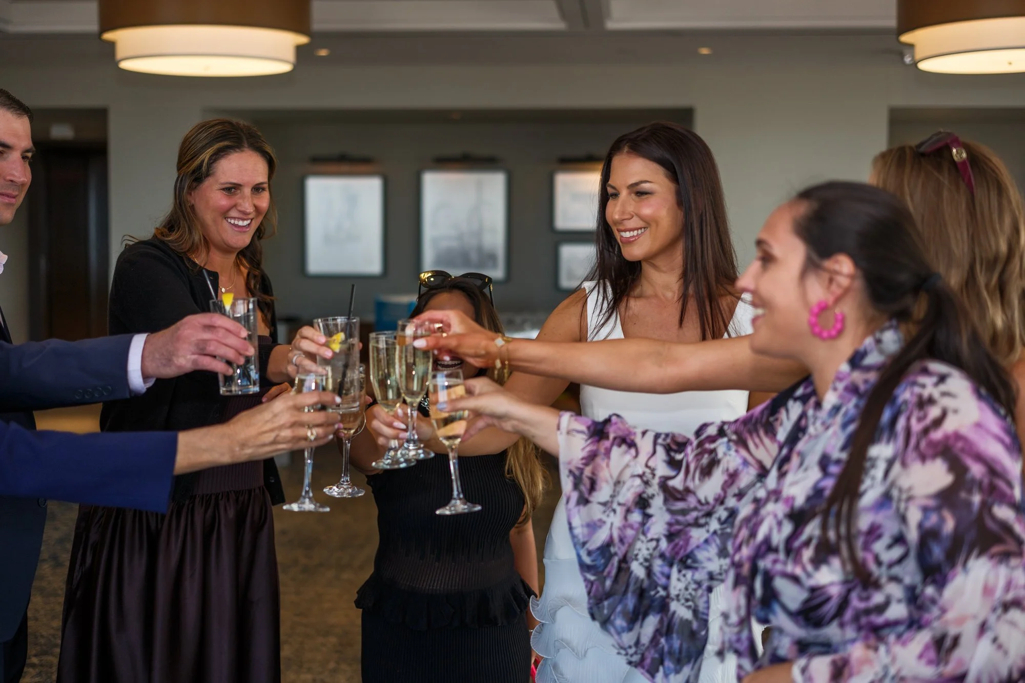 Bride Lauren and her guests raising champagne flutes and cocktail glasses in a joyful toast during the rehearsal dinner at the UMass Club in Boston
