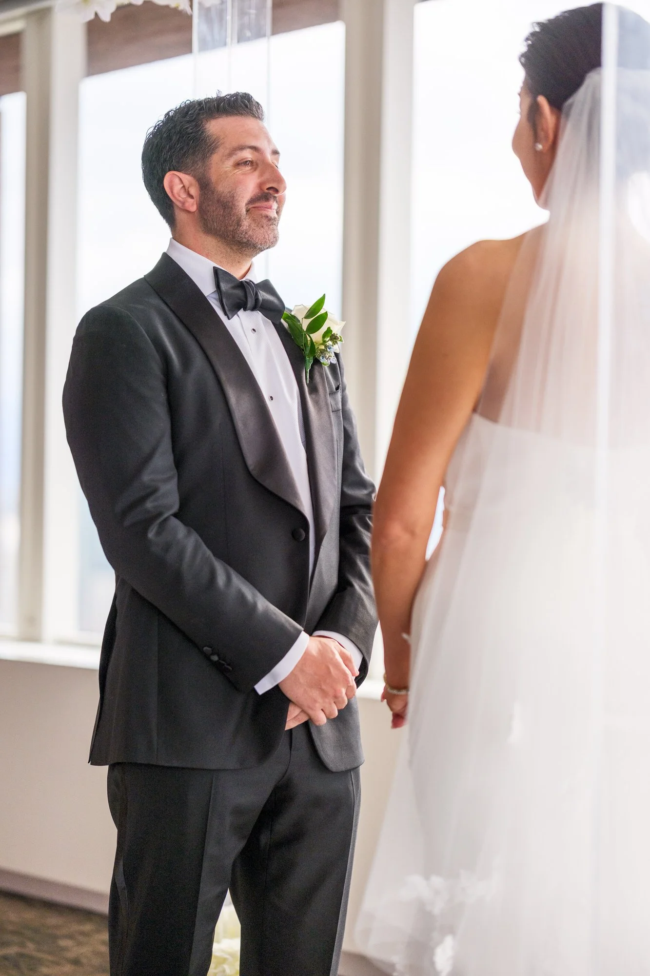 Emotional groom looking at bride during vows at the UMass Club Boston Jewish ceremony with chuppah visible