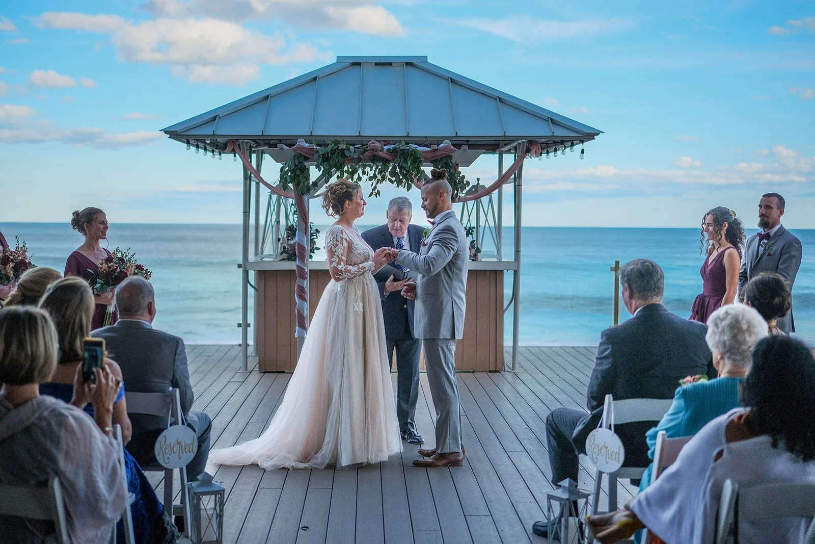 Couple exchanging rings under the oceanfront gazebo at Blue Ocean Event Center with Atlantic Ocean behind them