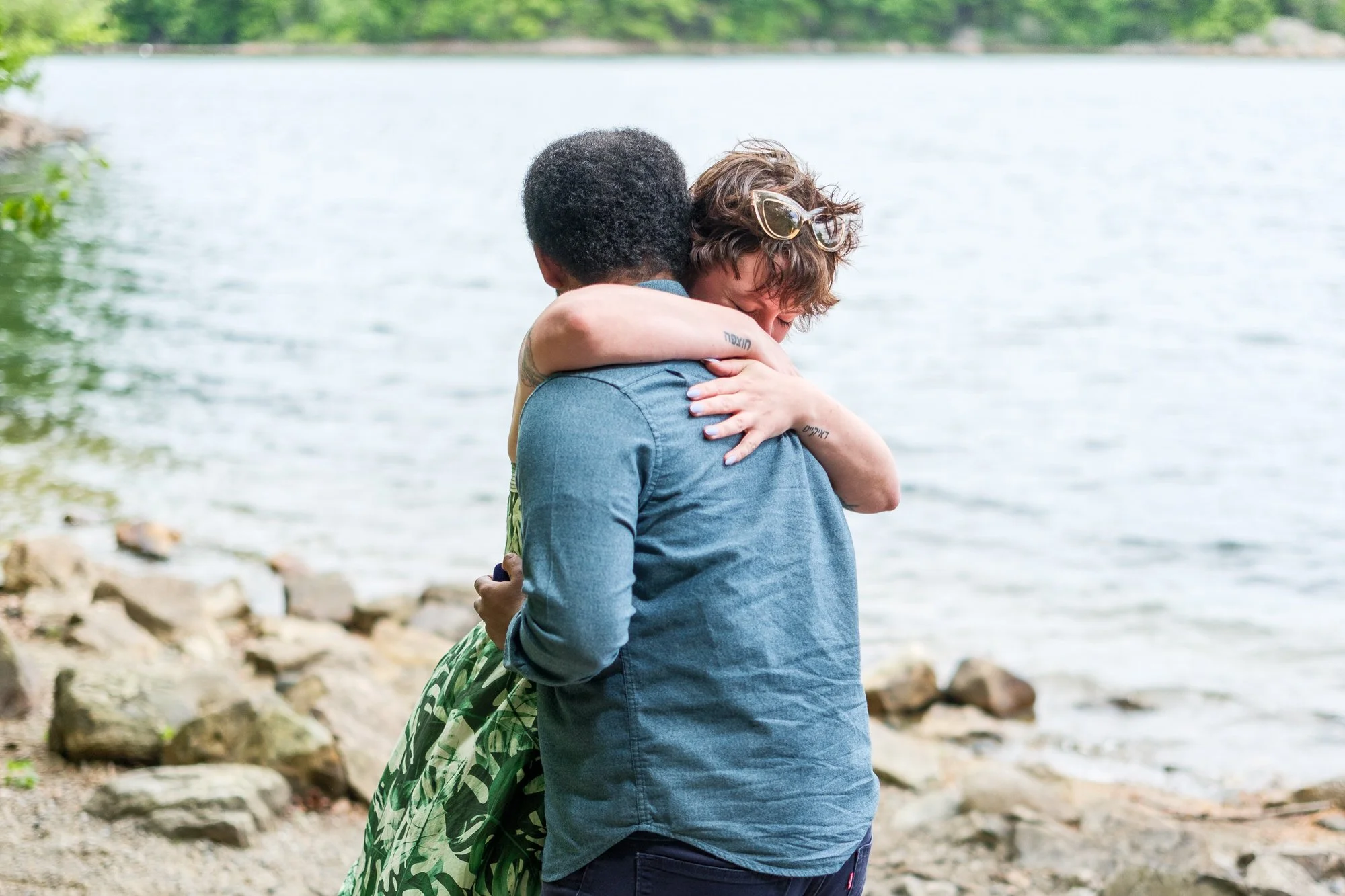 Newly engaged couple embracing after a waterfront proposal at Middlesex Fells Reservation
