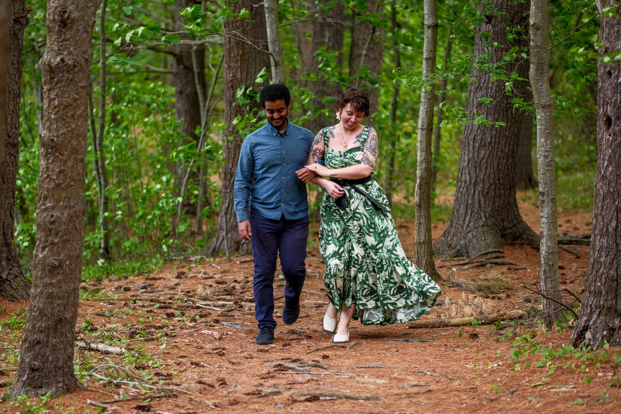 Couple walking hand in hand through the woods after their spring proposal