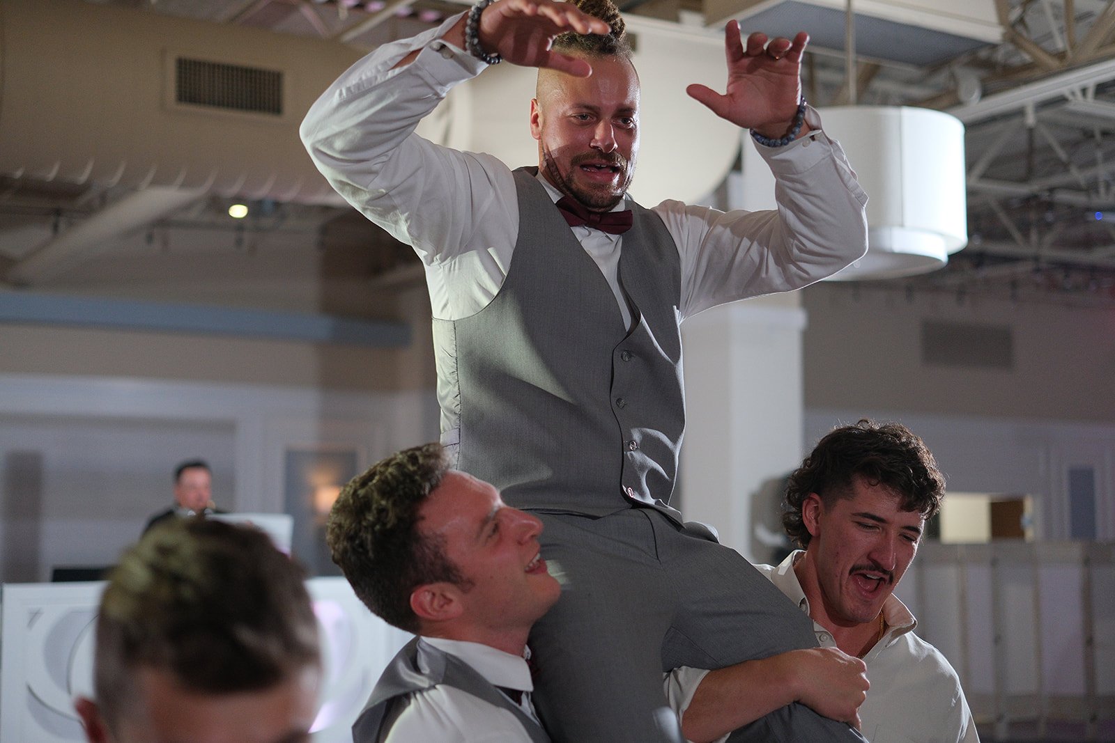 Groomsmen hoisting the groom on their shoulders during high-energy reception dancing at Blue Ocean Event Center