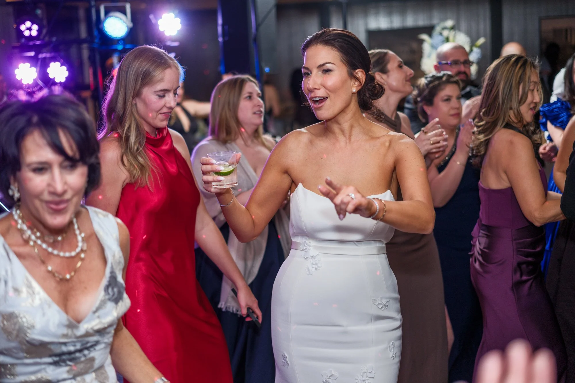 Bride dancing joyfully with guests on a packed dance floor at the UMass Club Boston Jewish wedding reception