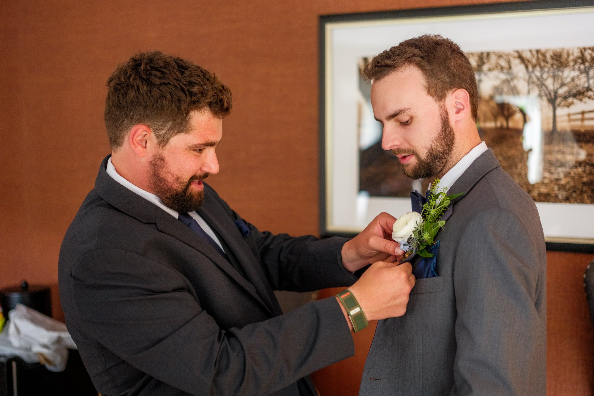 Groomsman pins boutonniere on groom before a Lake Morey Resort wedding ceremony