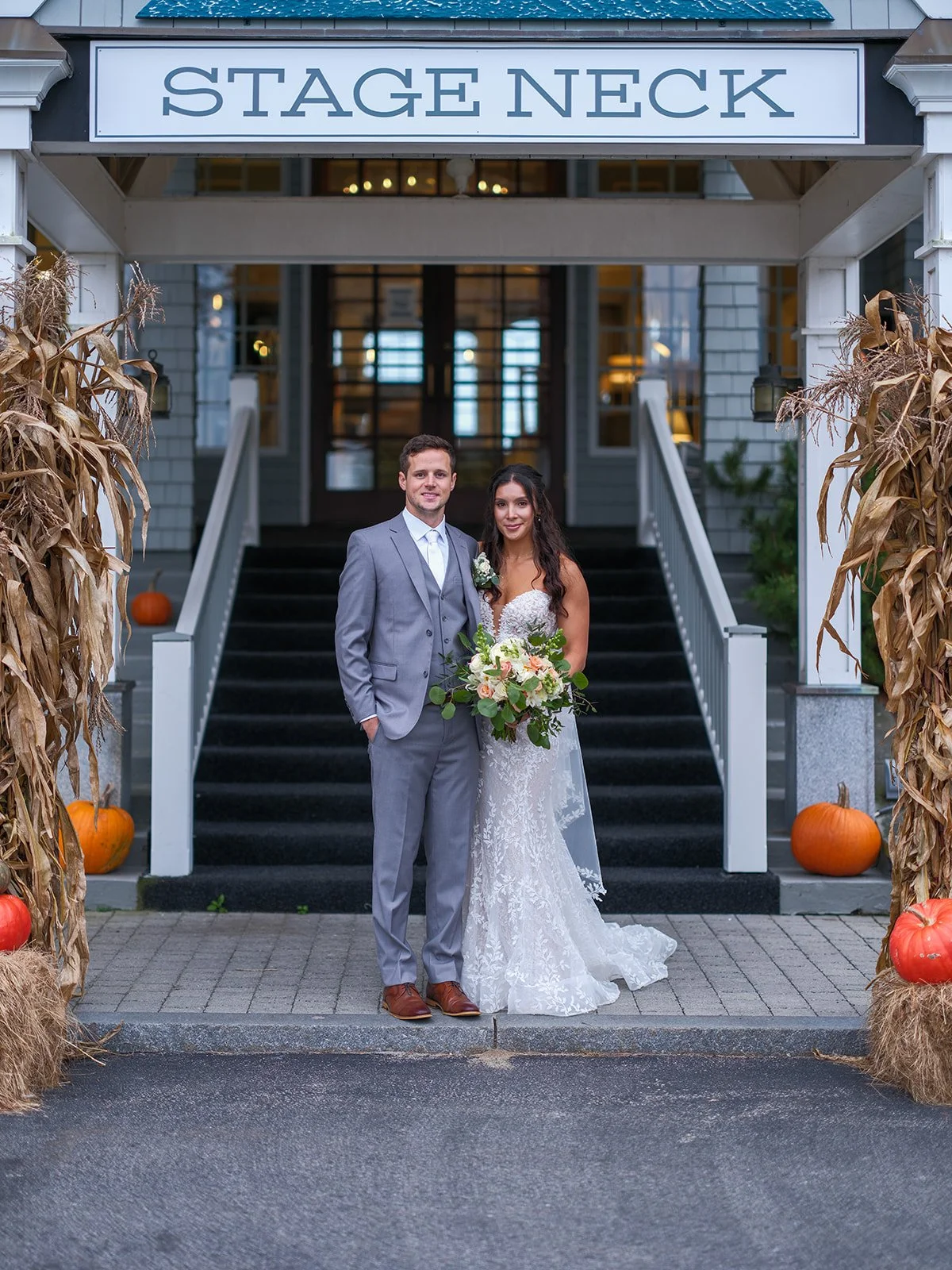 Bride and groom portrait in front of the Stage Neck Inn entrance with fall pumpkin decor in York Maine
