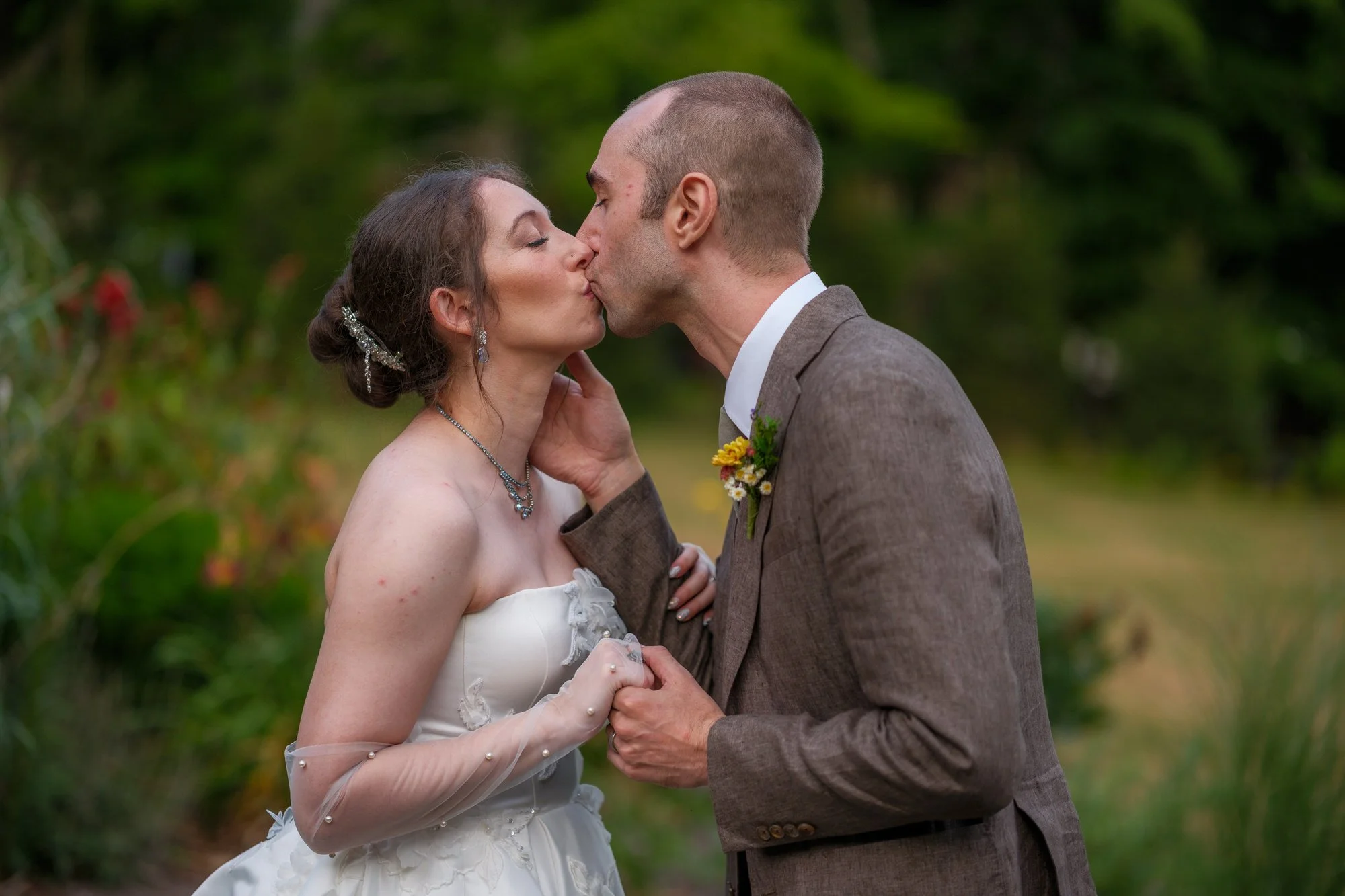 Close-up of bride and groom kissing with her bouquet between them
