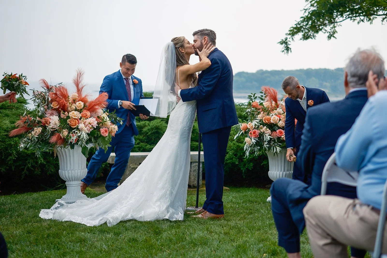Bride and groom share their first kiss during outdoor ceremony with ocean views in York Maine